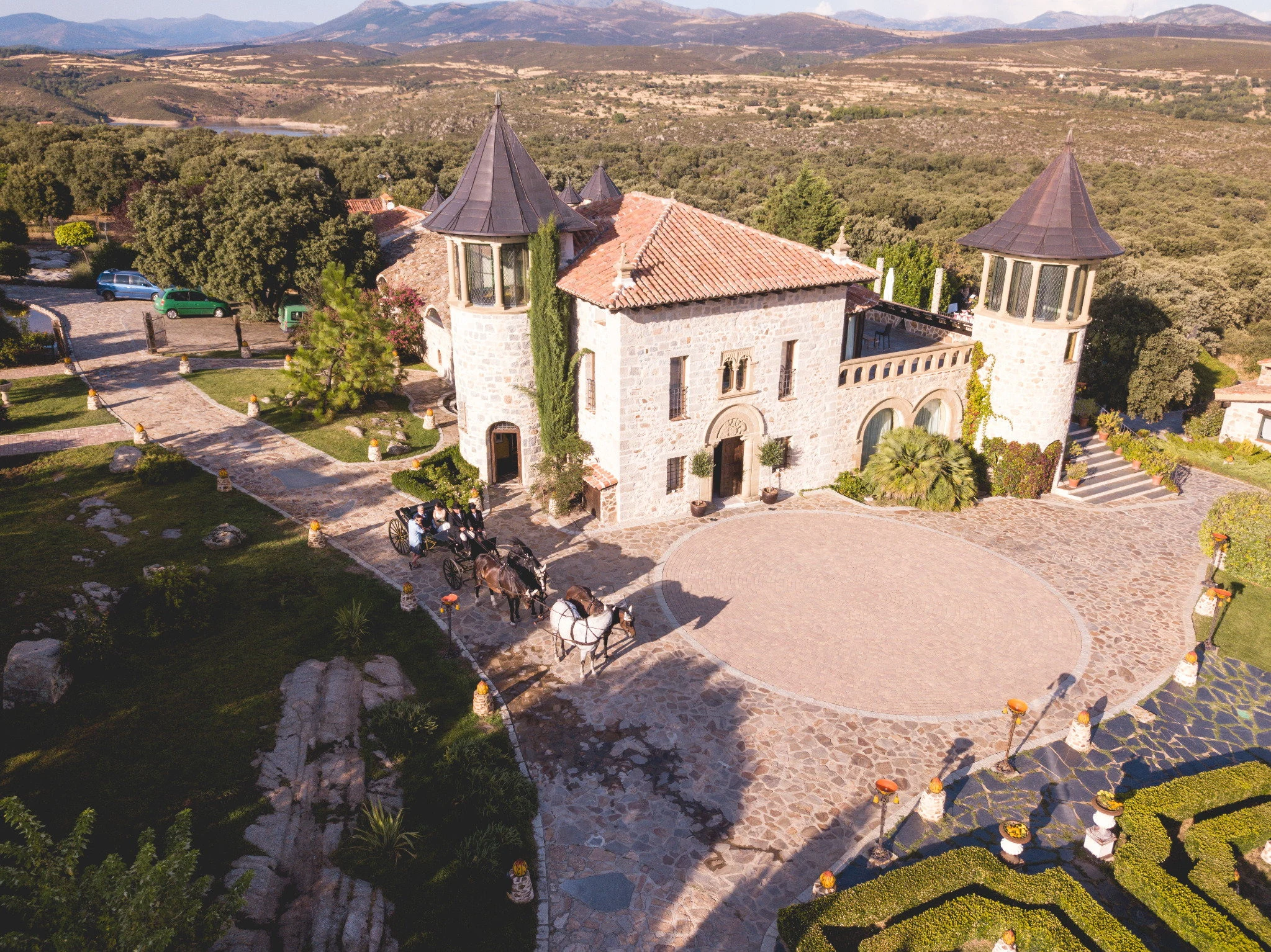 Vista aérea de la finca Aldea Santillana rodeada de jardines y la sierra de Madrid