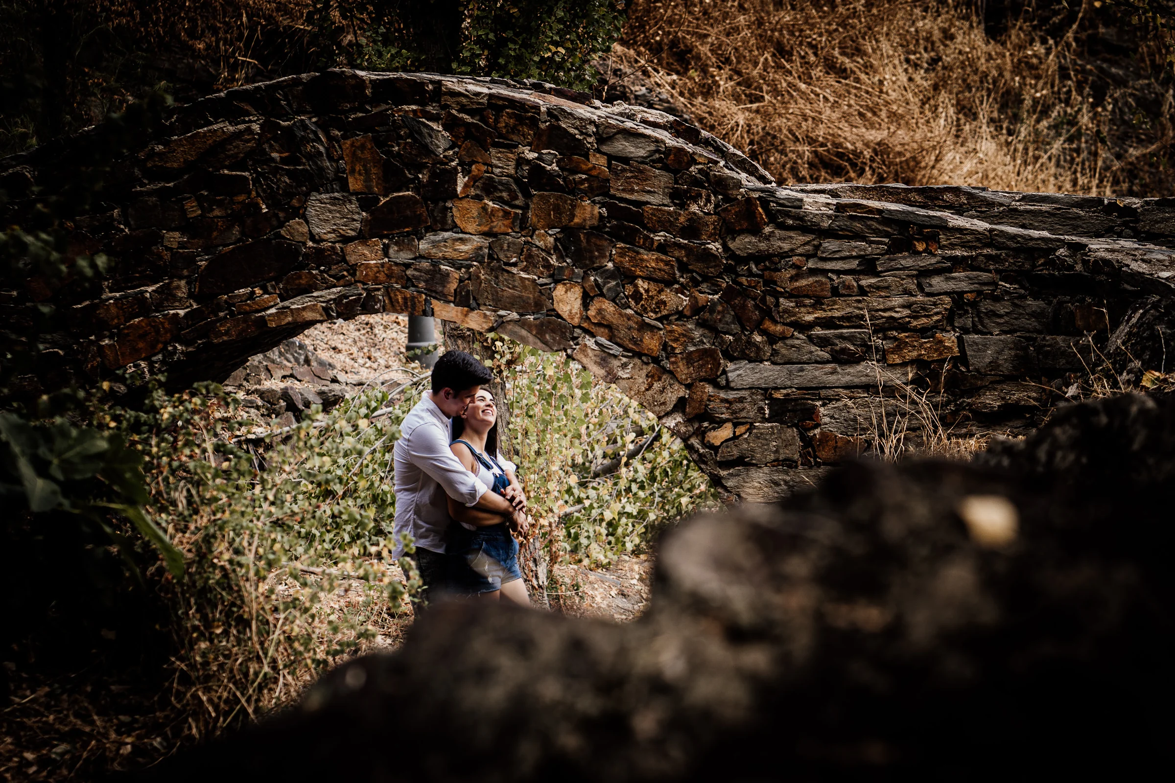 Aritz abraza a Laura bajo un arco de piedra durante su preboda por el entorno de Patones.
