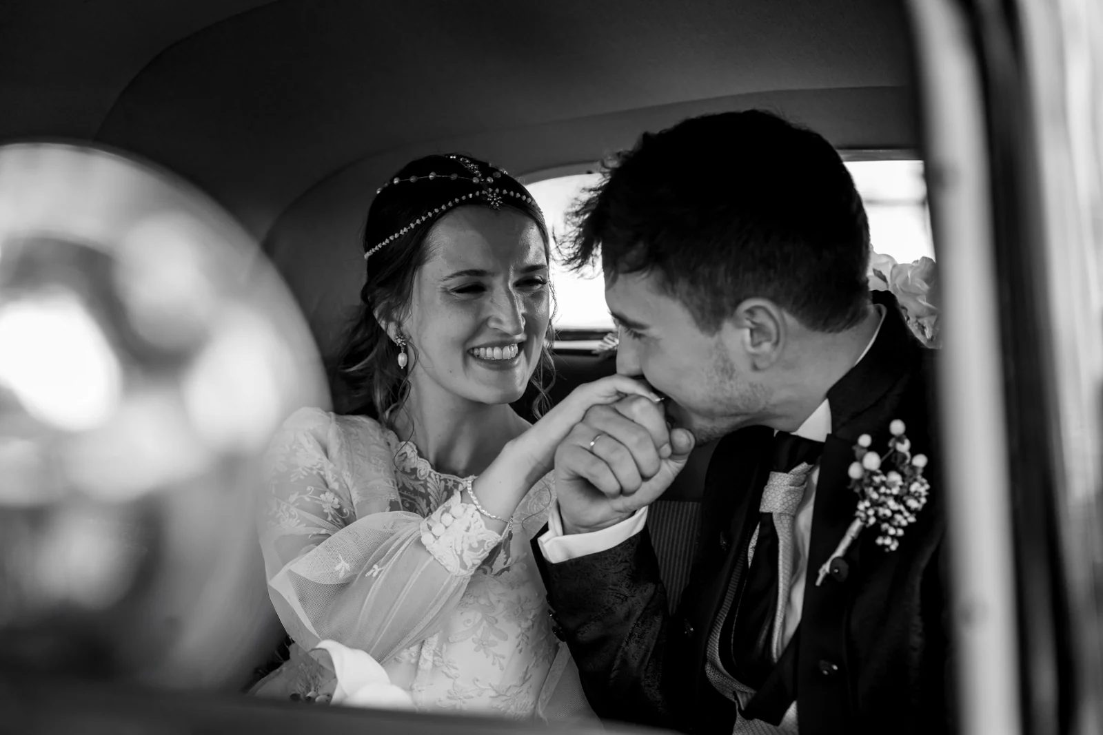 Novio besando la mano de la novia en el coche