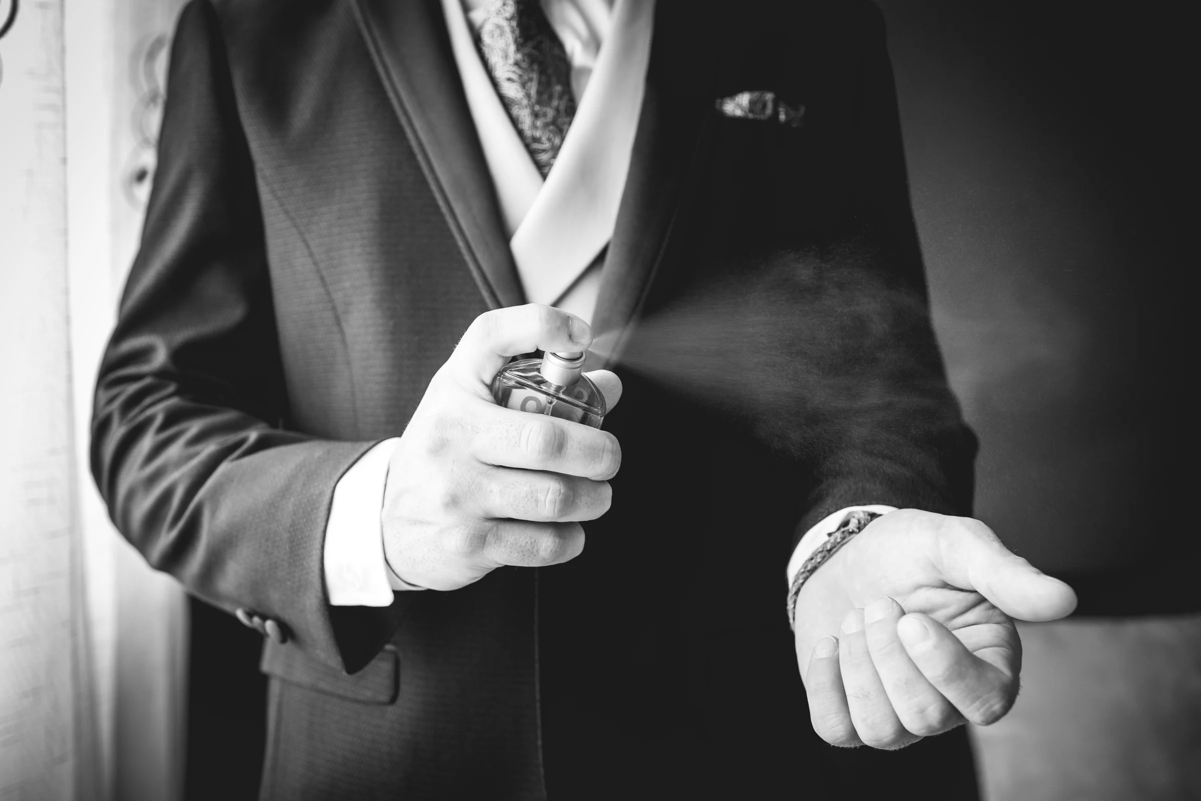 Detalle del novio ajustándose el traje y el reloj, fotografía de boda en el Castillo de Viñuelas.