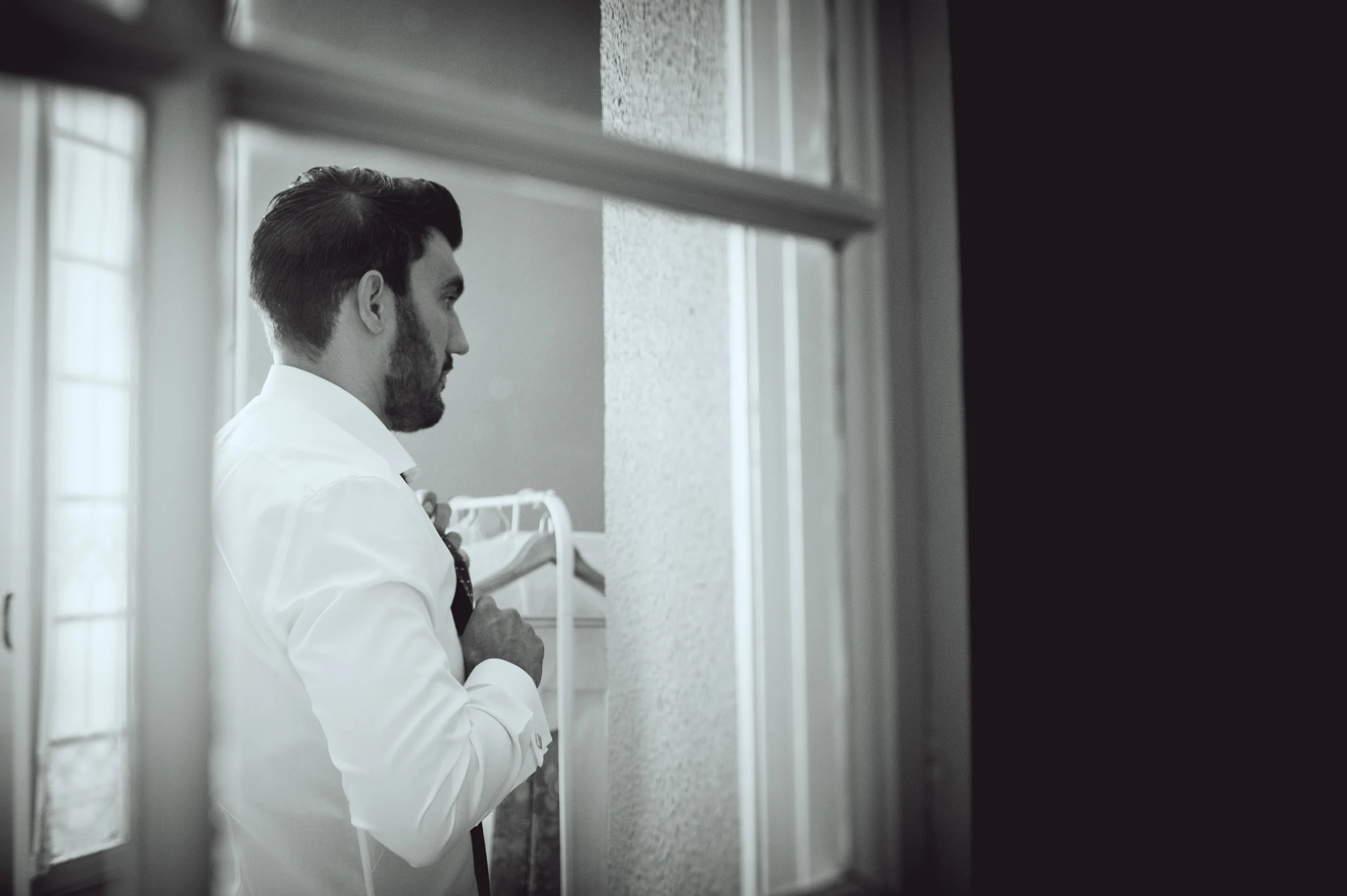 Novio junto a la ventana durante los preparativos, fotografía de boda en el Castillo de Viñuelas.