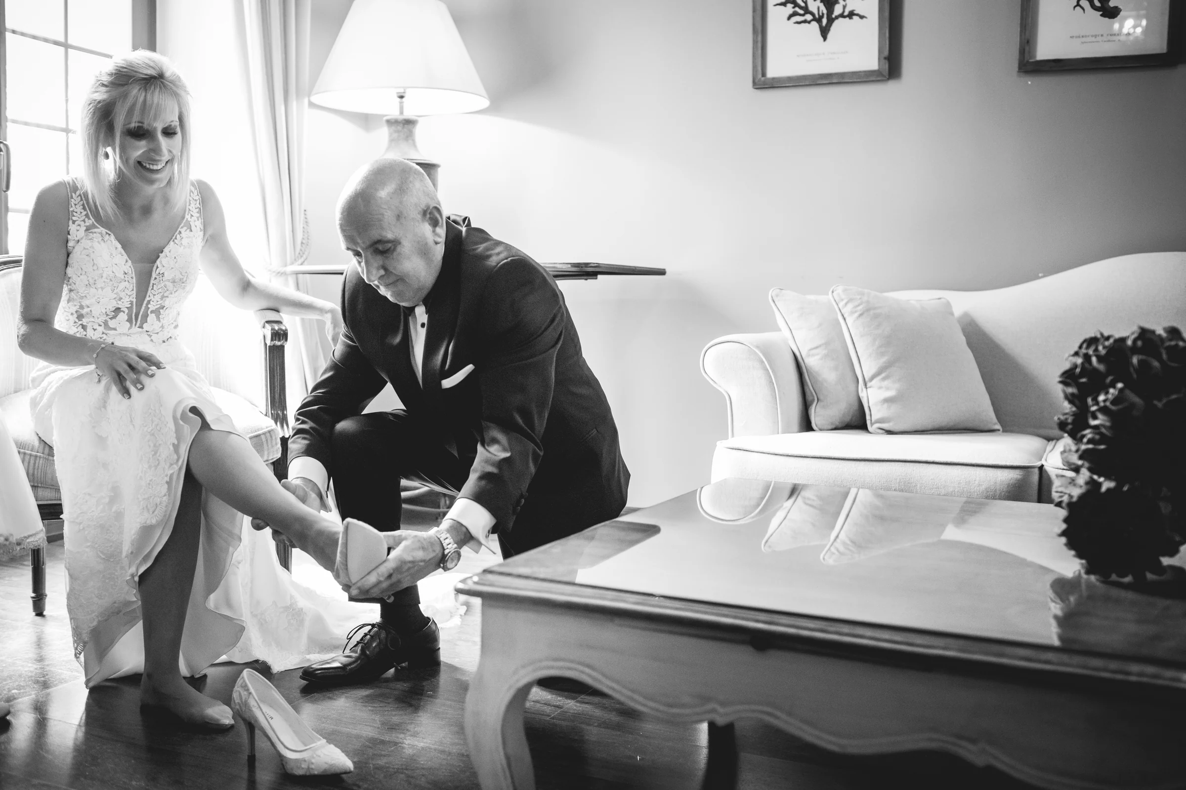 Padre ayudando a la novia a ponerse los zapatos, fotografía de boda en el Castillo de Viñuelas.