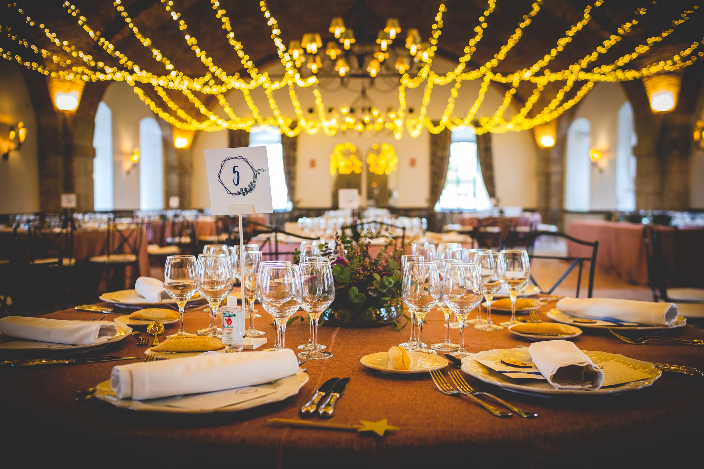Mesa de banquete decorada con luces calidas, fotografía de boda en el Castillo de Viñuelas.