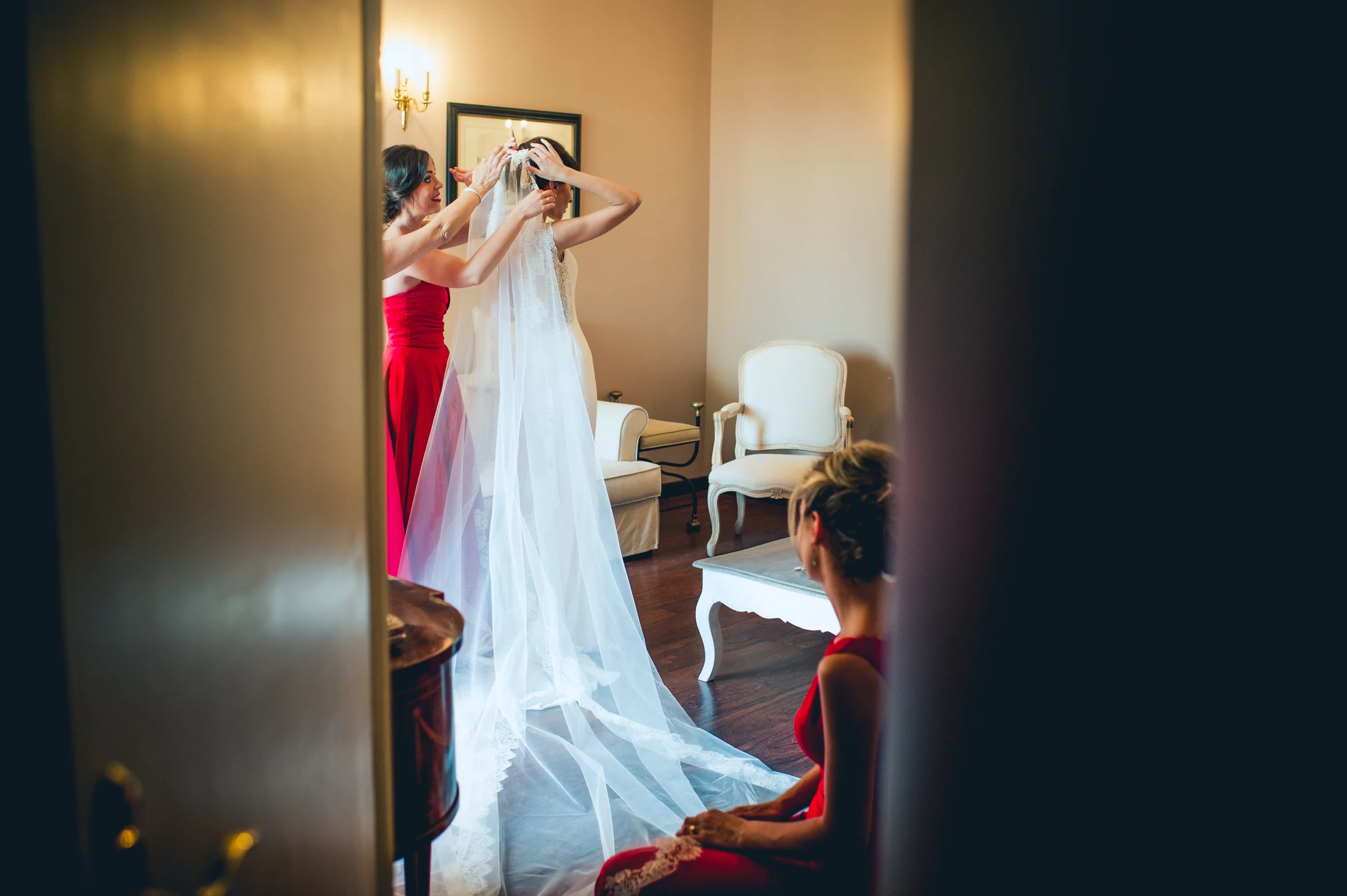 Novia terminando de vestirse con ayuda de una acompañante, fotografía de boda en el Castillo de Viñuelas.