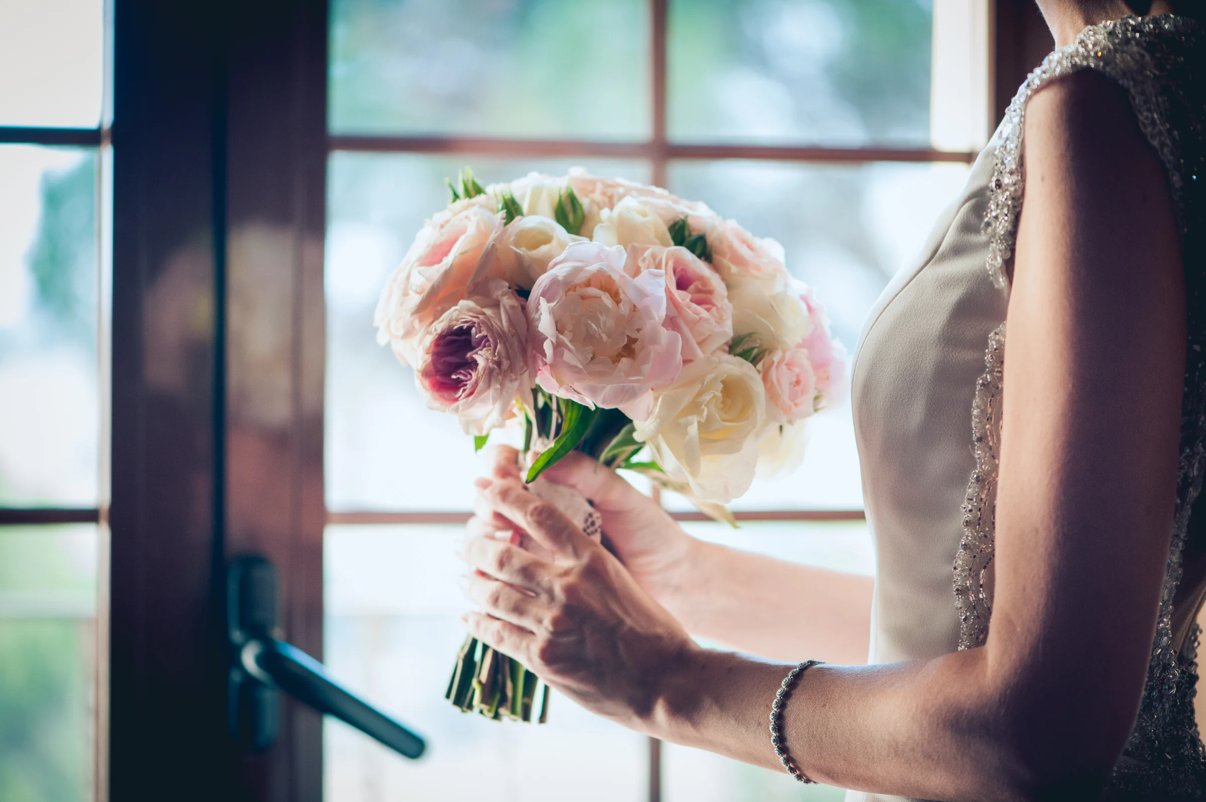 Detalle del ramo de novia sostenido entre las manos, fotografía de boda en el Castillo de Viñuelas.