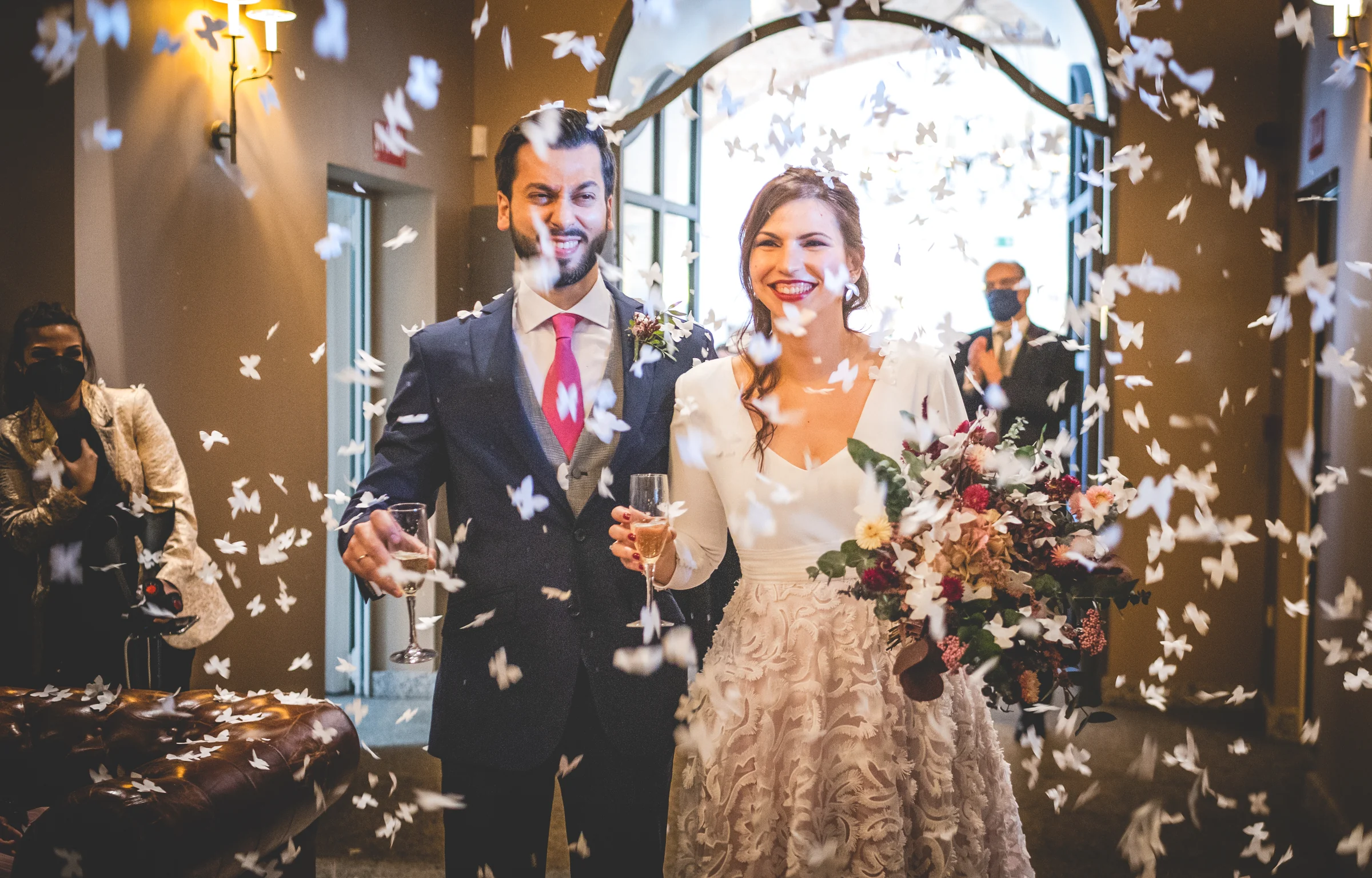 Novios saliendo entre confeti y aplausos, fotografía de boda en el Castillo de Viñuelas.