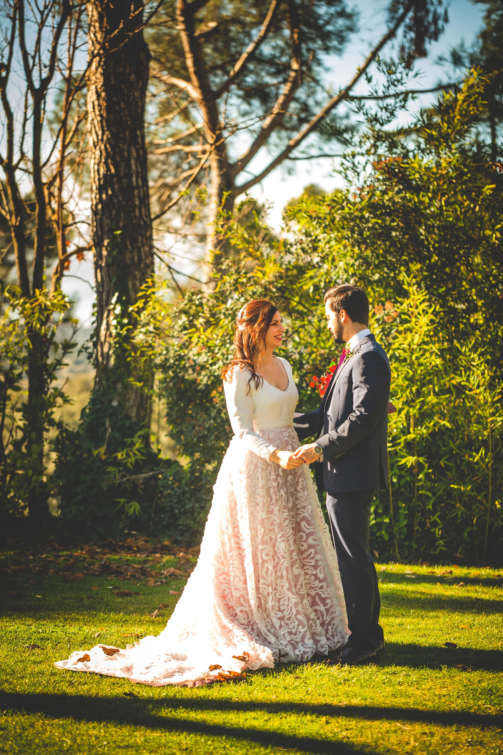 Novios posando entre arboles con luz dorada, fotografía de boda en el Castillo de Viñuelas.