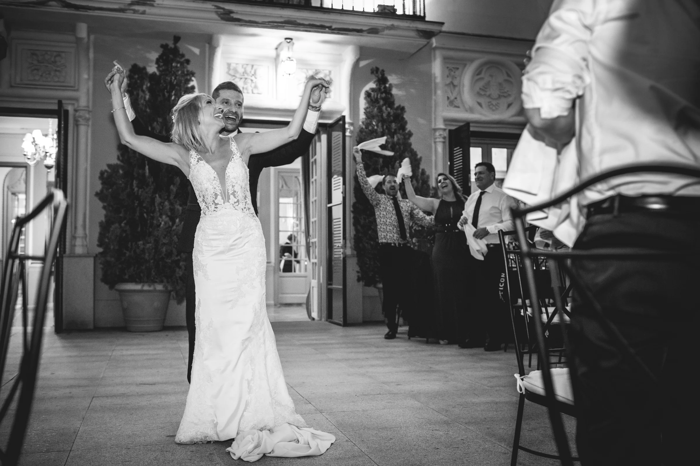 Novia entrando al salon del banquete con los brazos en alto, fotografía de boda en el Castillo de Viñuelas.