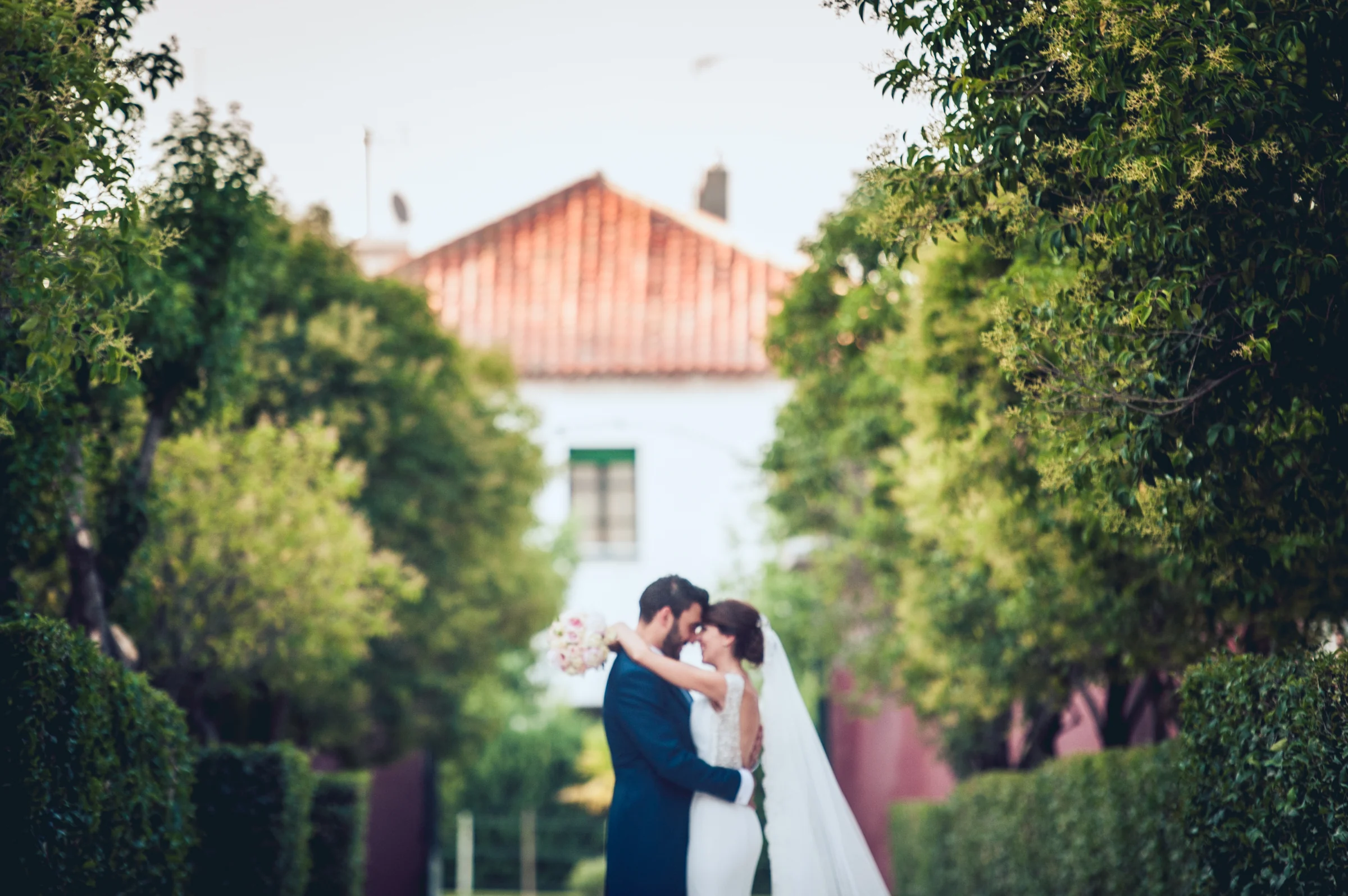 Novios posando al fondo de un camino ajardinado, fotografía de boda en el Castillo de Viñuelas.