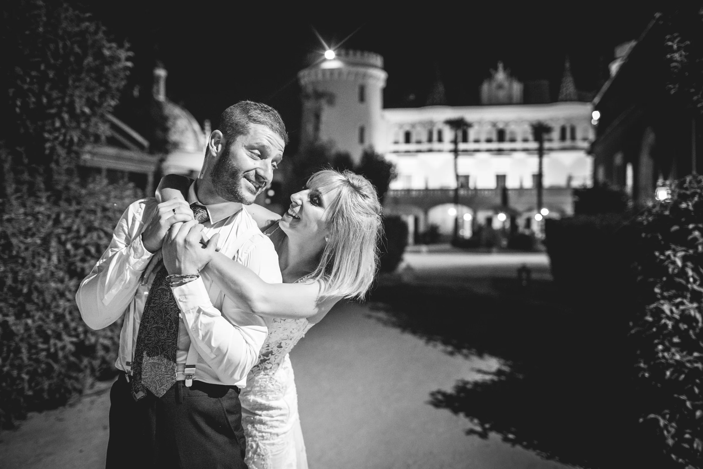 Novio levantando a la novia de noche frente al castillo, fotografía de boda en el Castillo de Viñuelas.