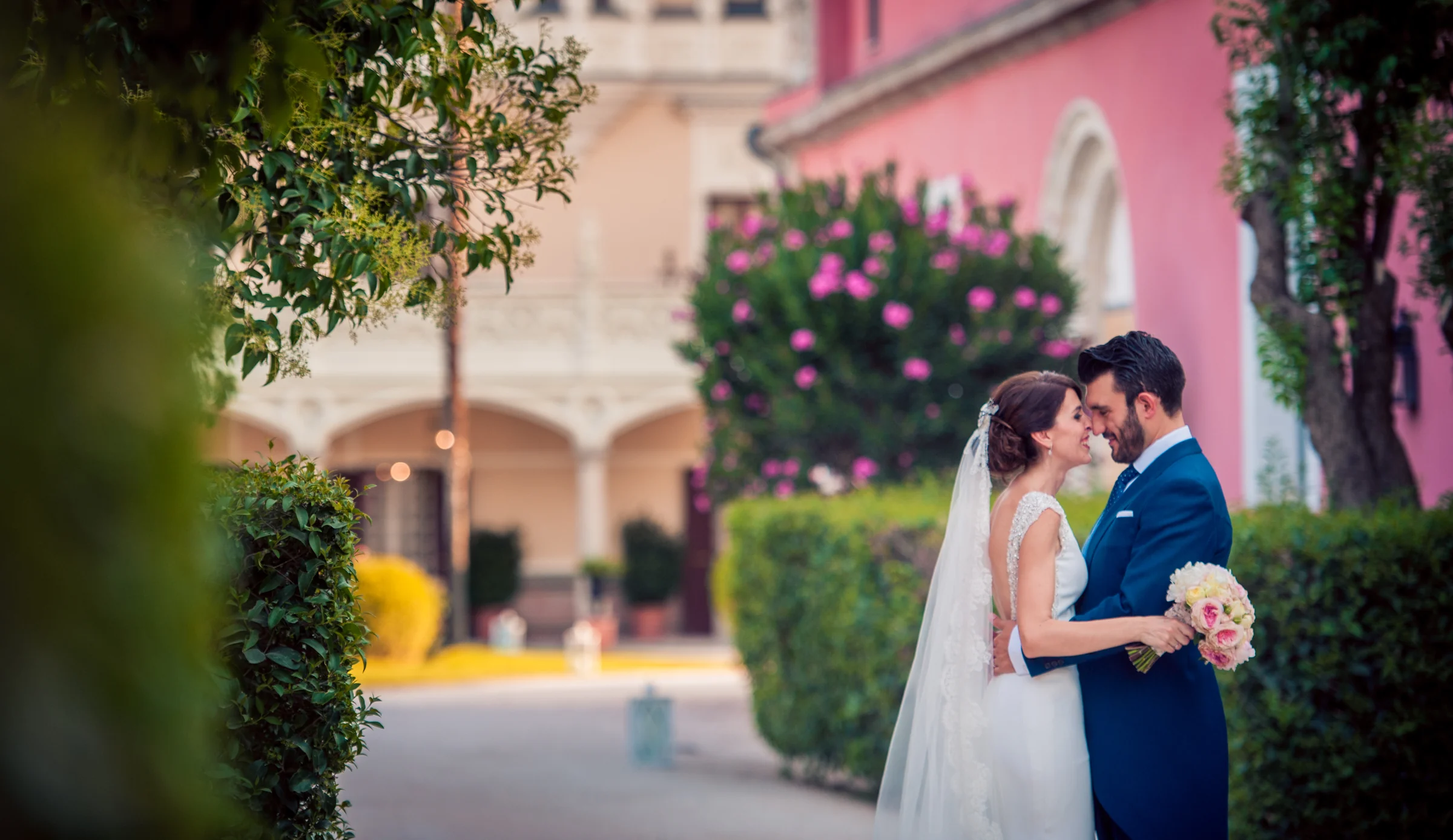 Novios besándose entre flores y jardines, fotografía de boda en el Castillo de Viñuelas.