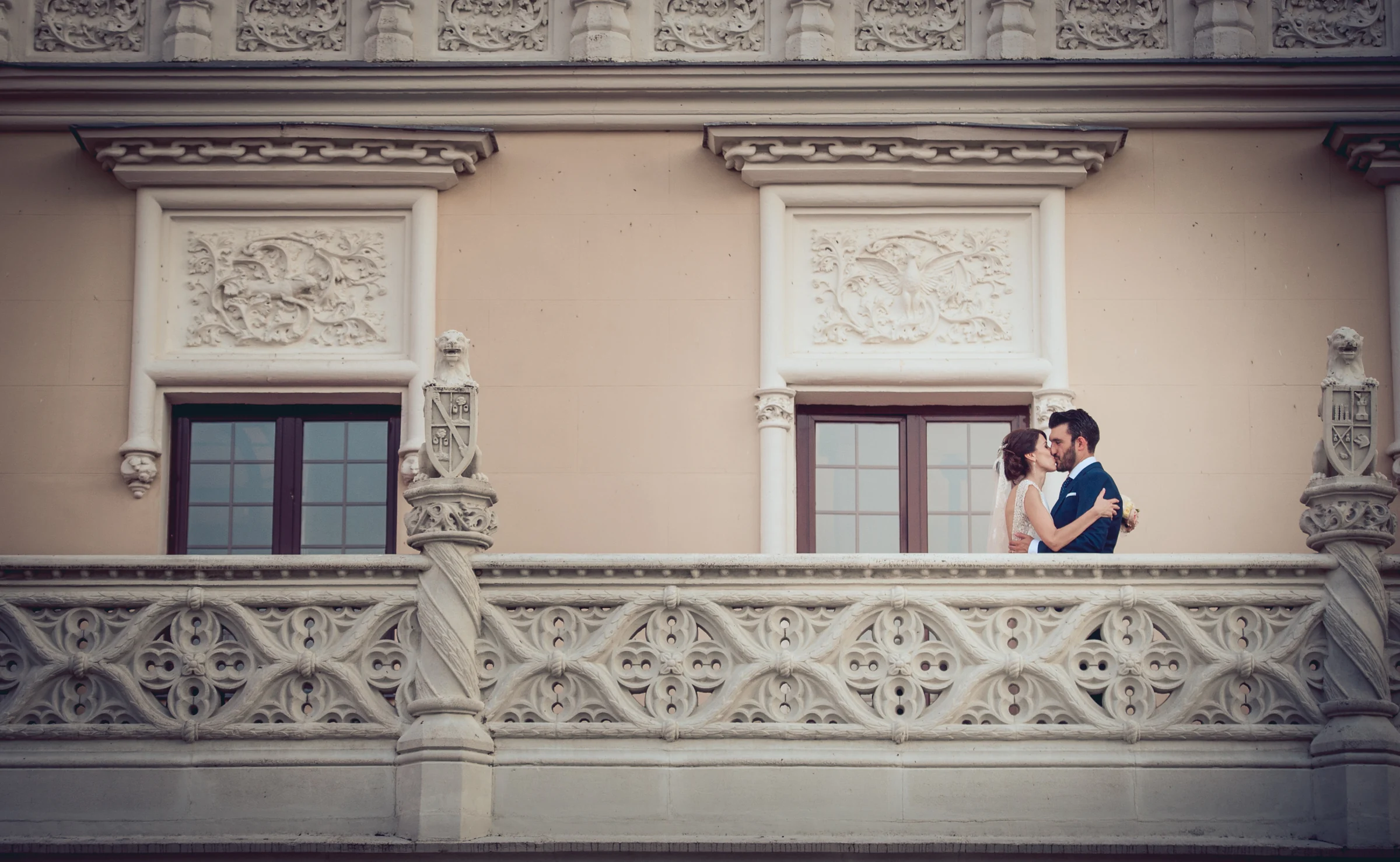 Novios besándose en el balcón exterior del castillo, fotografía de boda en el Castillo de Viñuelas.