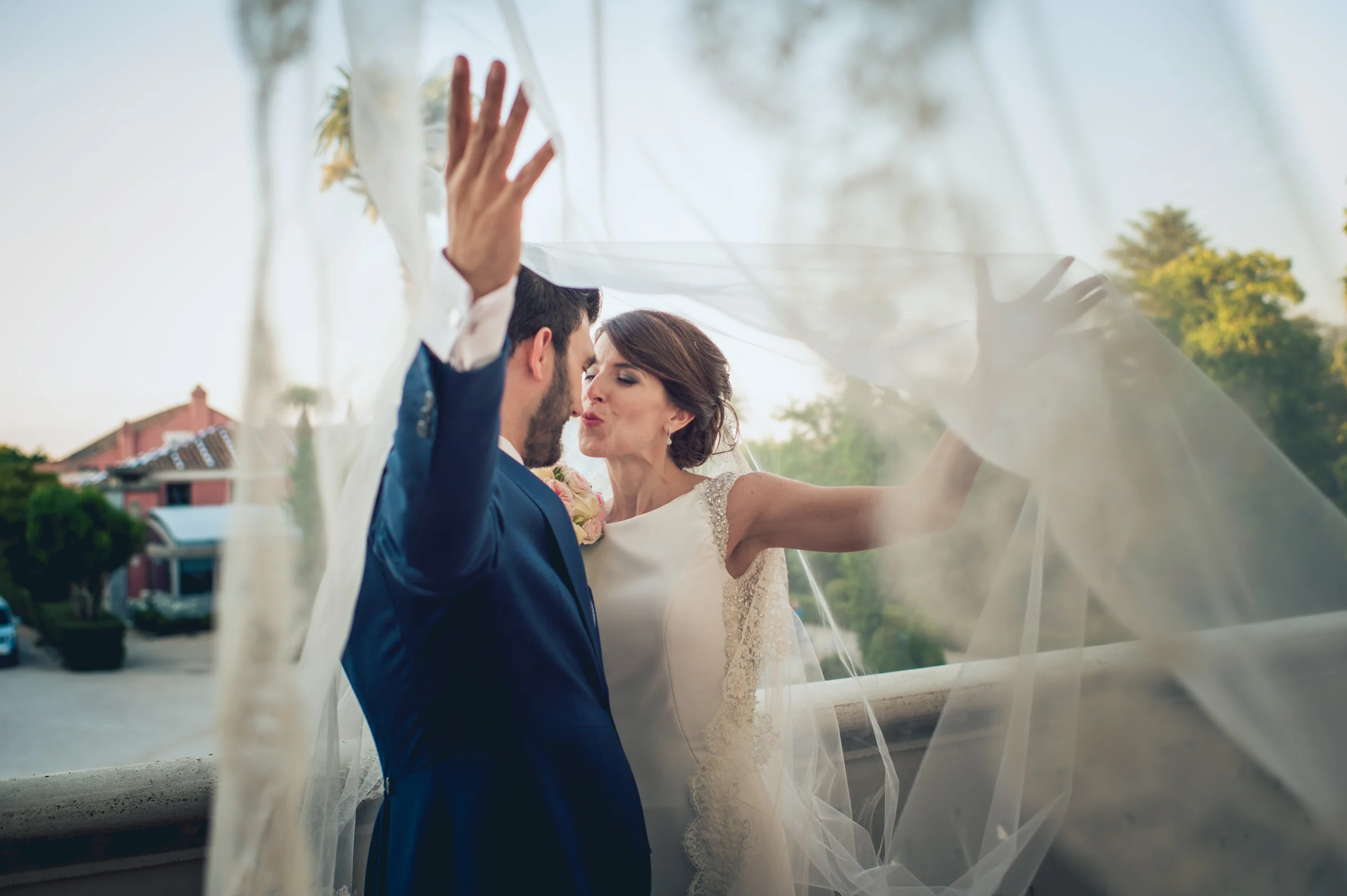 Novios jugando con el velo en una terraza, fotografía de boda en el Castillo de Viñuelas.
