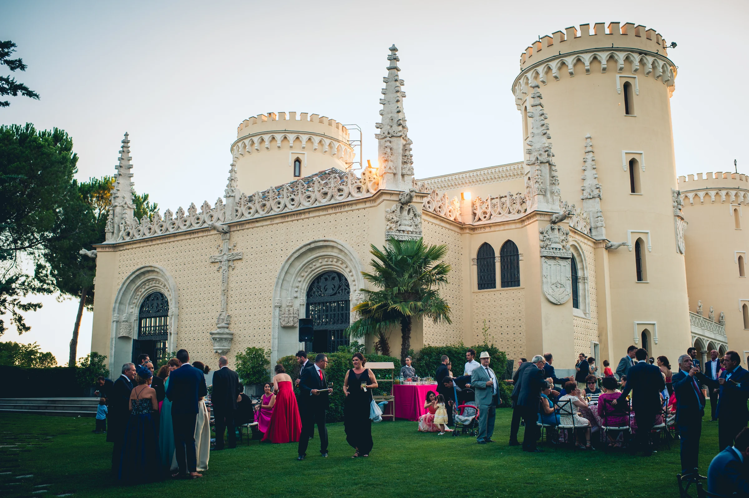 Invitados reunidos en el jardín junto al edificio, fotografía de boda en el Castillo de Viñuelas.