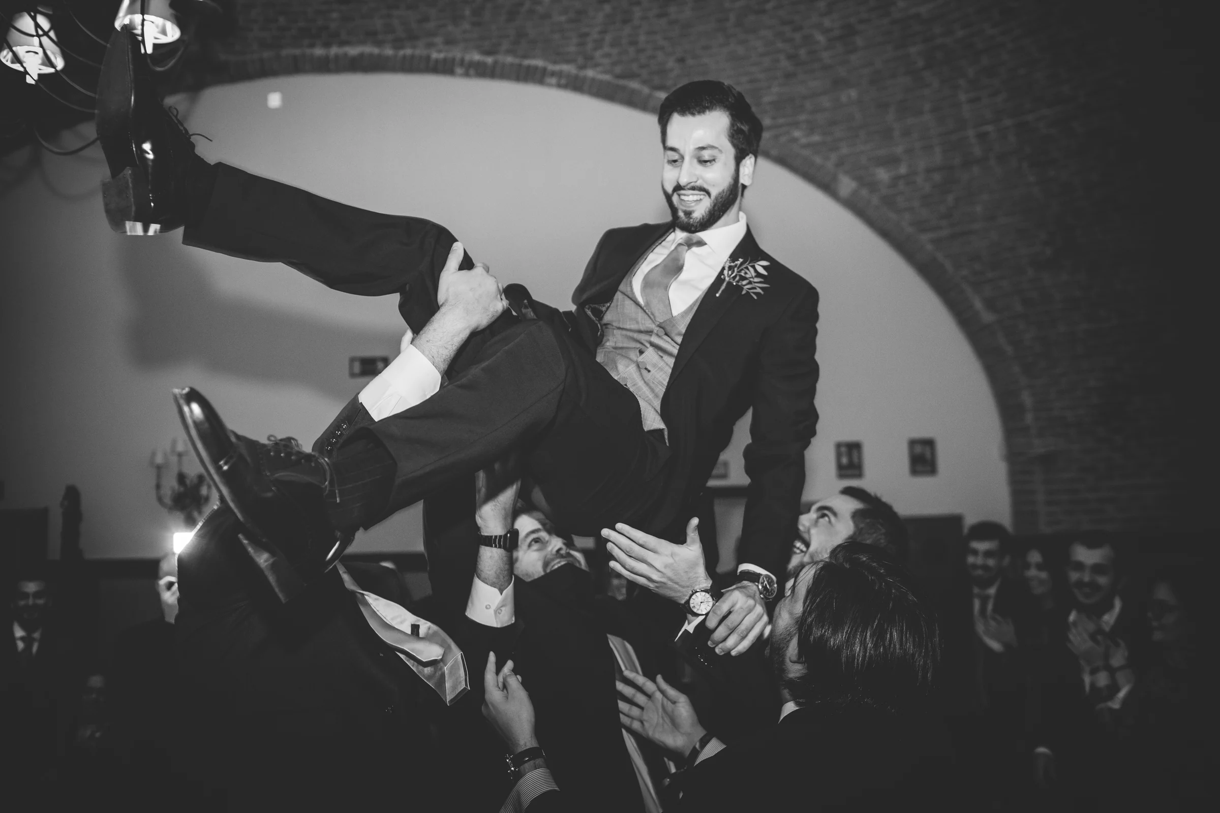 Novio levantado por sus amigos durante la fiesta, fotografía de boda en el Castillo de Viñuelas.