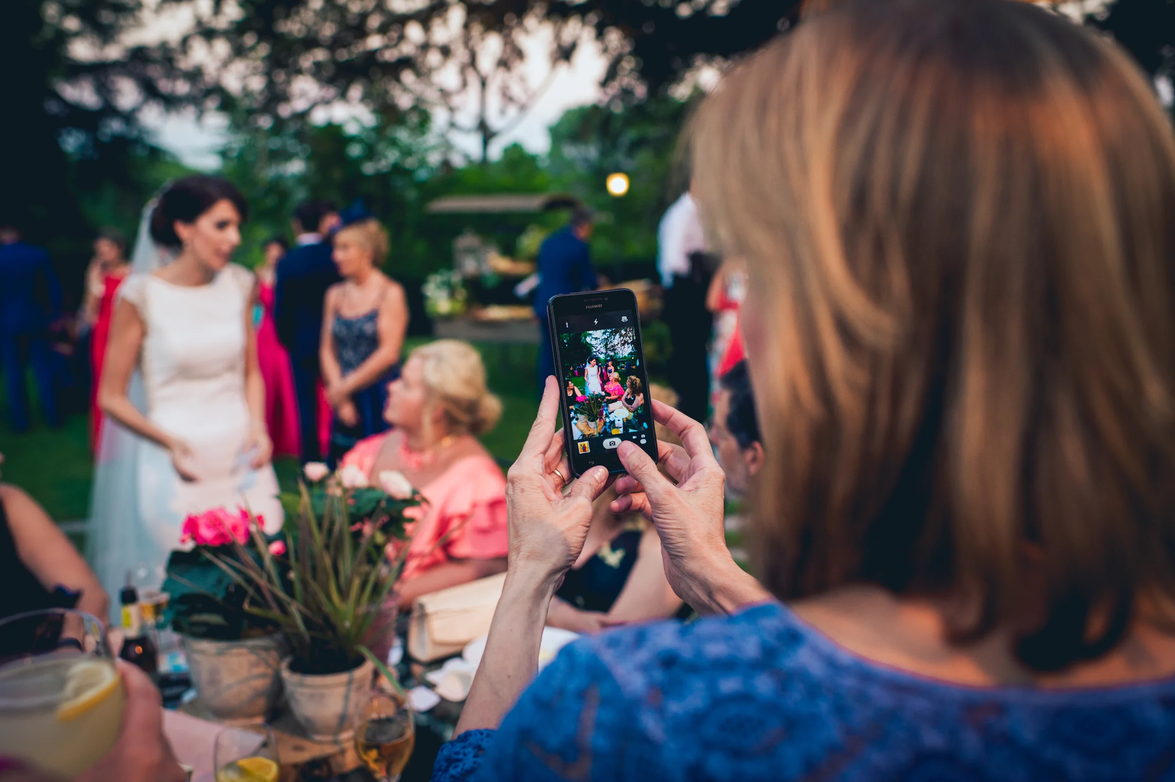 Novia enseñando el ramo a una invitada que toma una foto, fotografía de boda en el Castillo de Viñuelas.