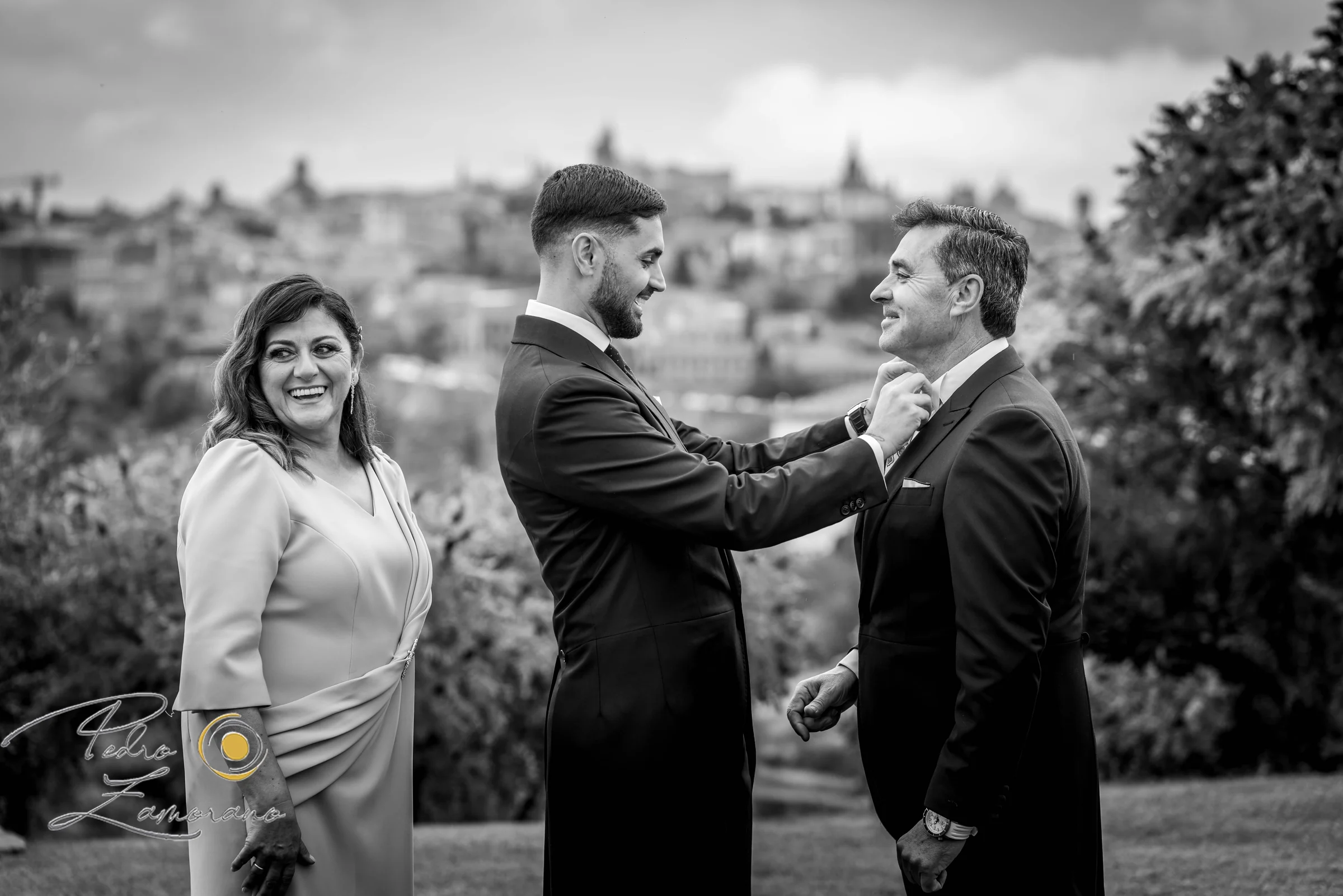 Novio acompañado por familiares con el perfil de Toledo al fondo en blanco y negro.