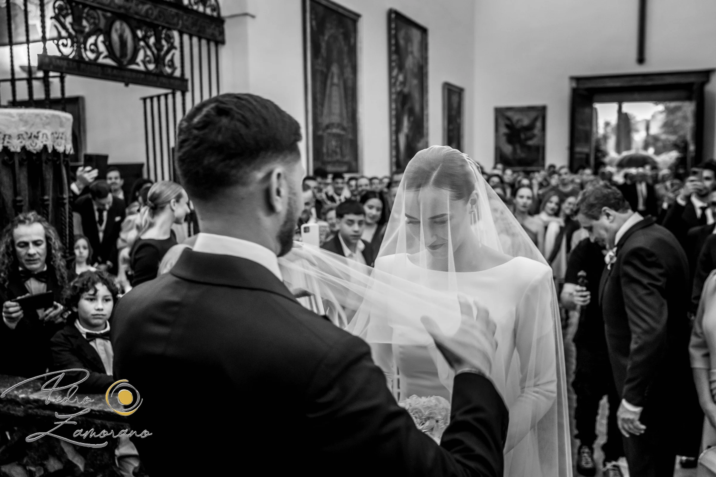 Novios e invitados durante la ceremonia en una fotografía en blanco y negro.