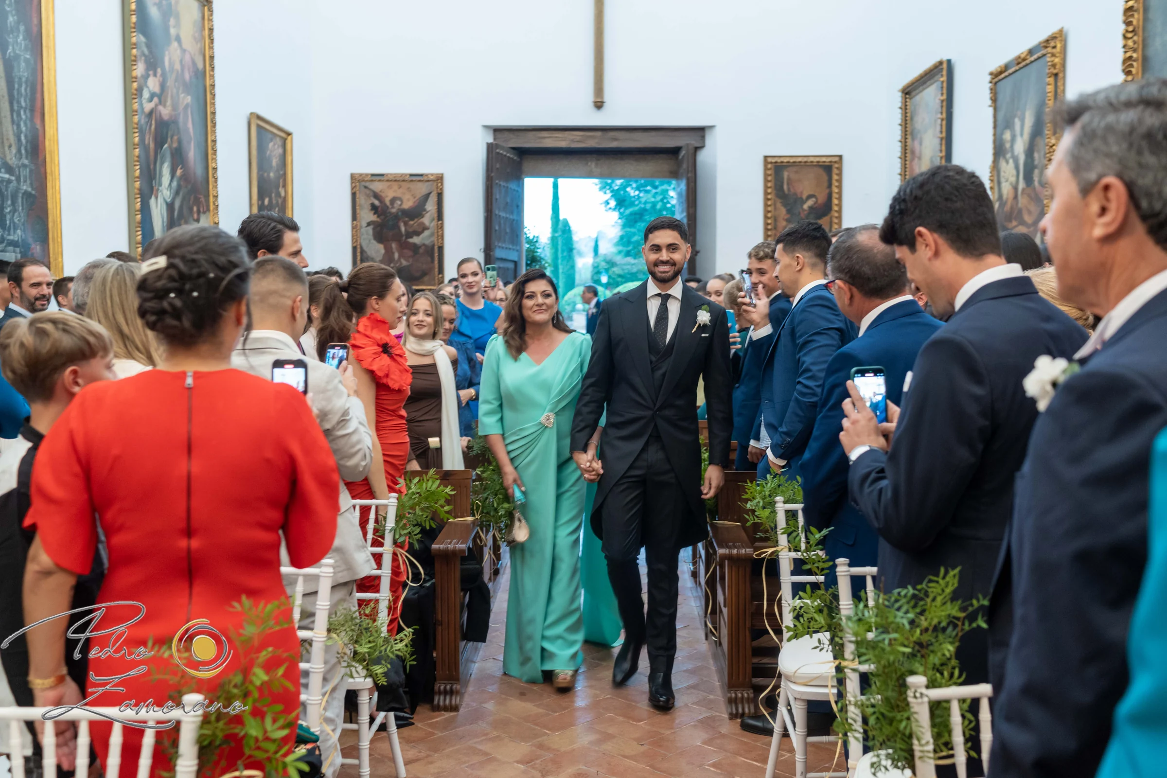 Novia avanzando por el pasillo de ceremonia entre familiares e invitados.
