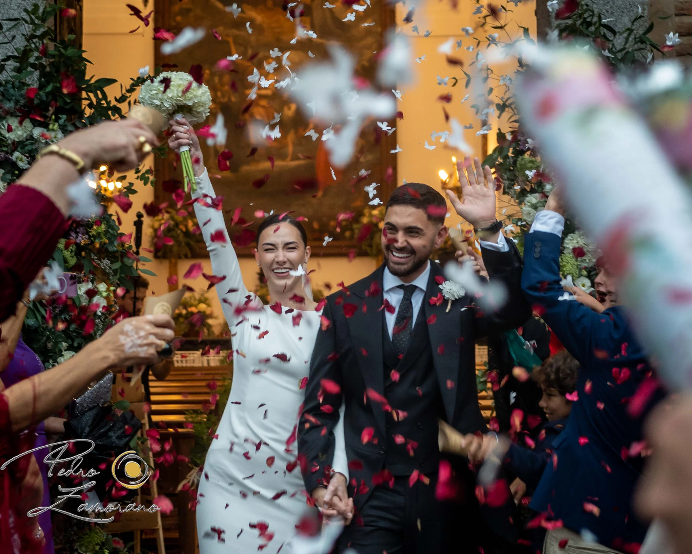 Novios celebrando su salida de la ceremonia entre pétalos y confeti.