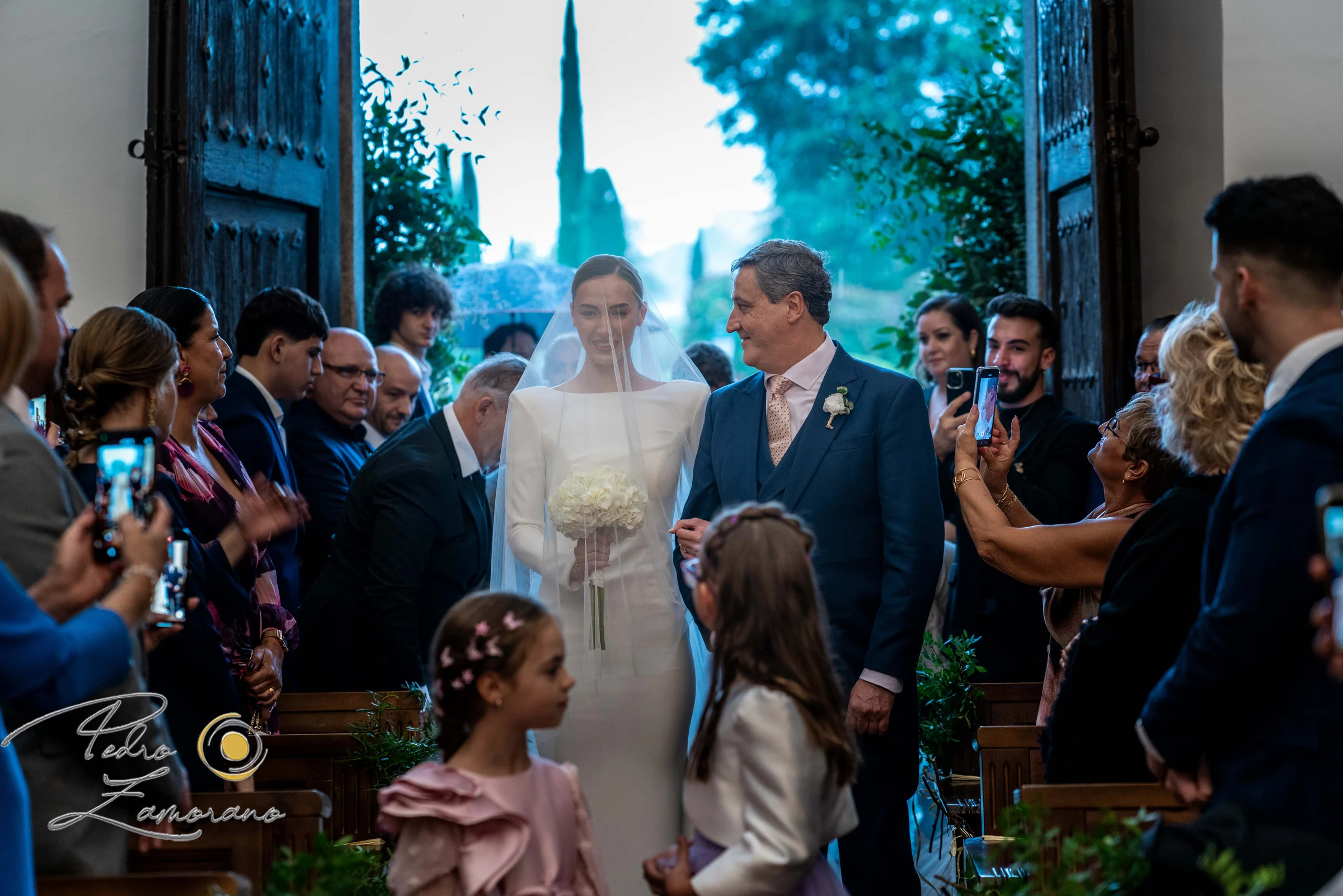 Novios saliendo de la ceremonia rodeados por invitados.