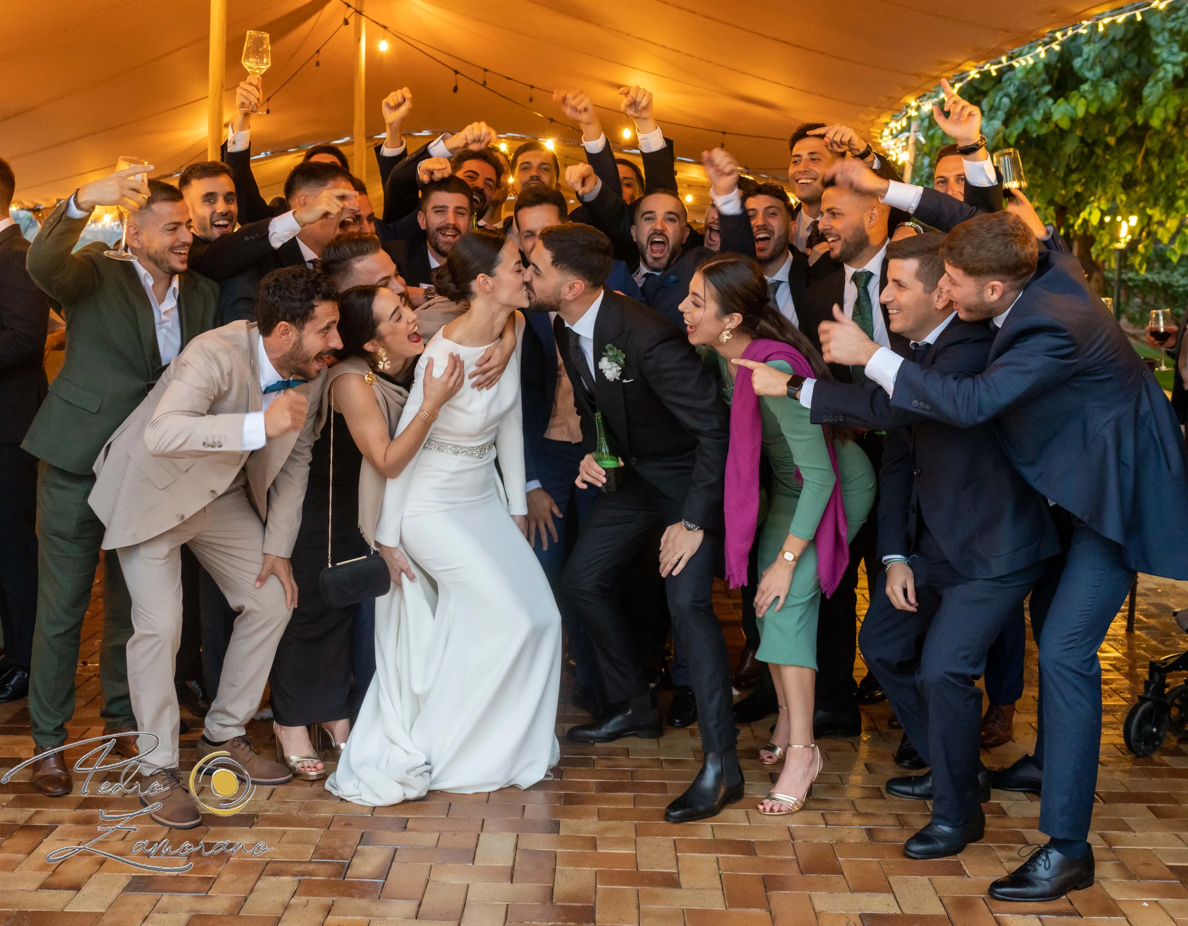 Novios rodeados por amigos e invitados durante una fotografía de grupo.