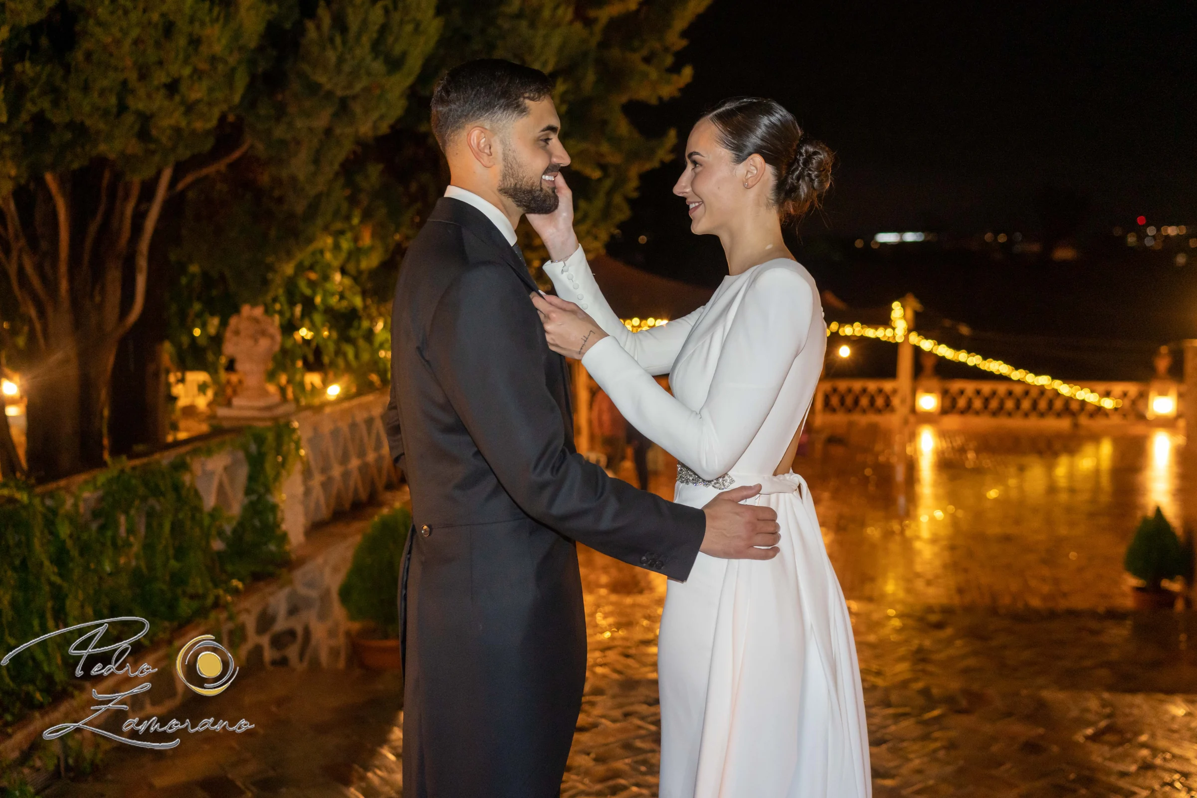 Novios abrazados durante una fotografía nocturna en los jardines.