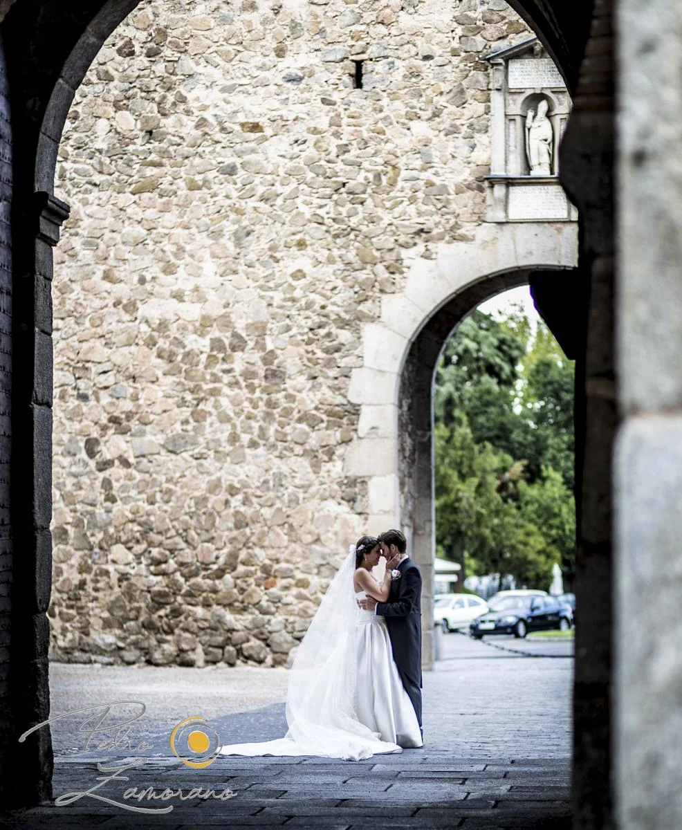Novia retratada bajo una puerta histórica de Toledo.