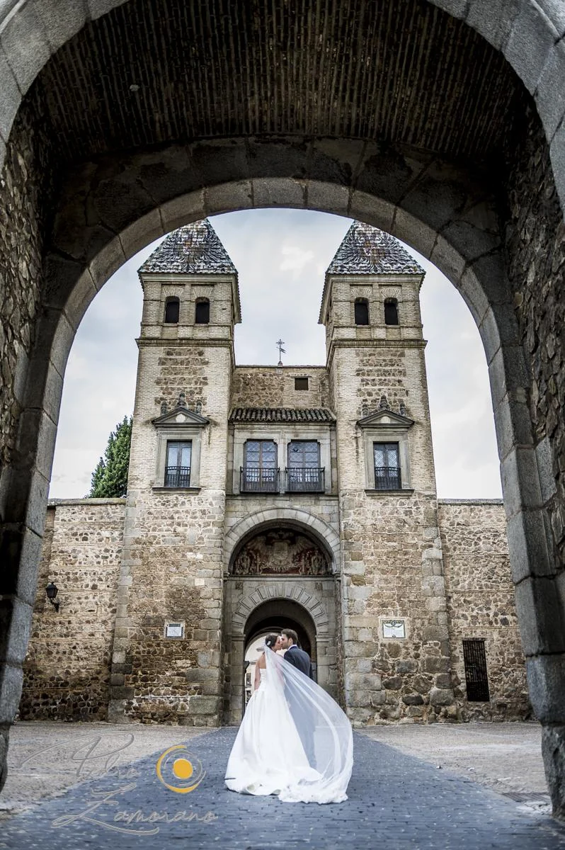 Novia enmarcada por un arco histórico durante el reportaje de boda en Toledo.