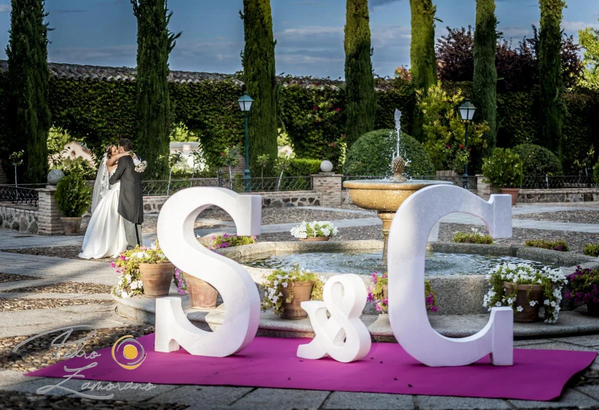 Novios junto a una decoración con sus iniciales en los jardines.