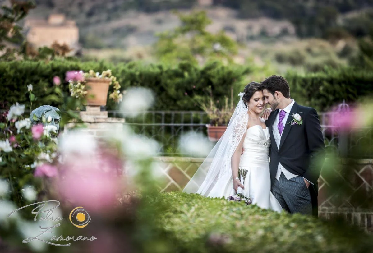 Novios en un jardín con flores durante su sesión de pareja.