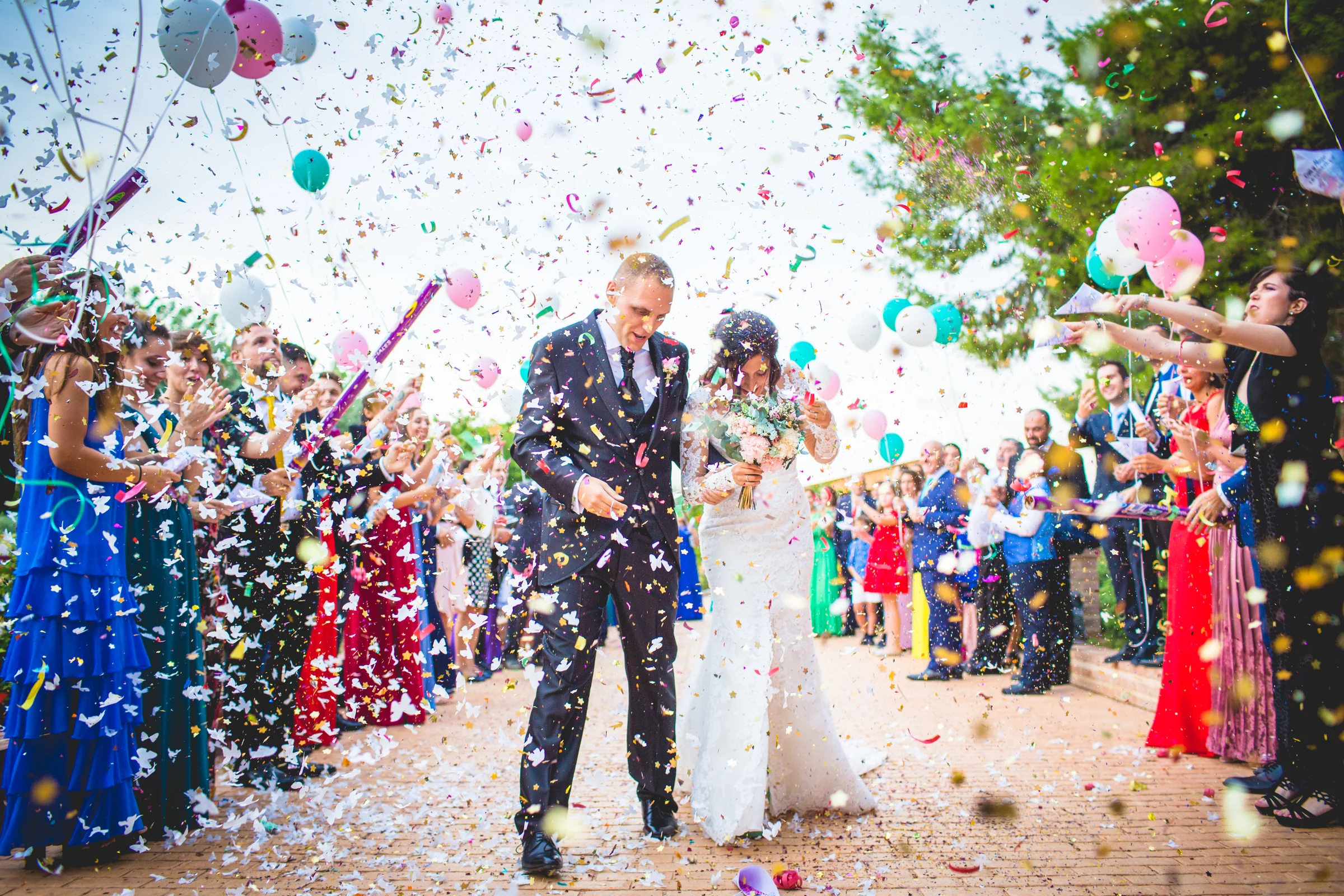 Novios celebrando la salida de la ceremonia entre confeti de colores.