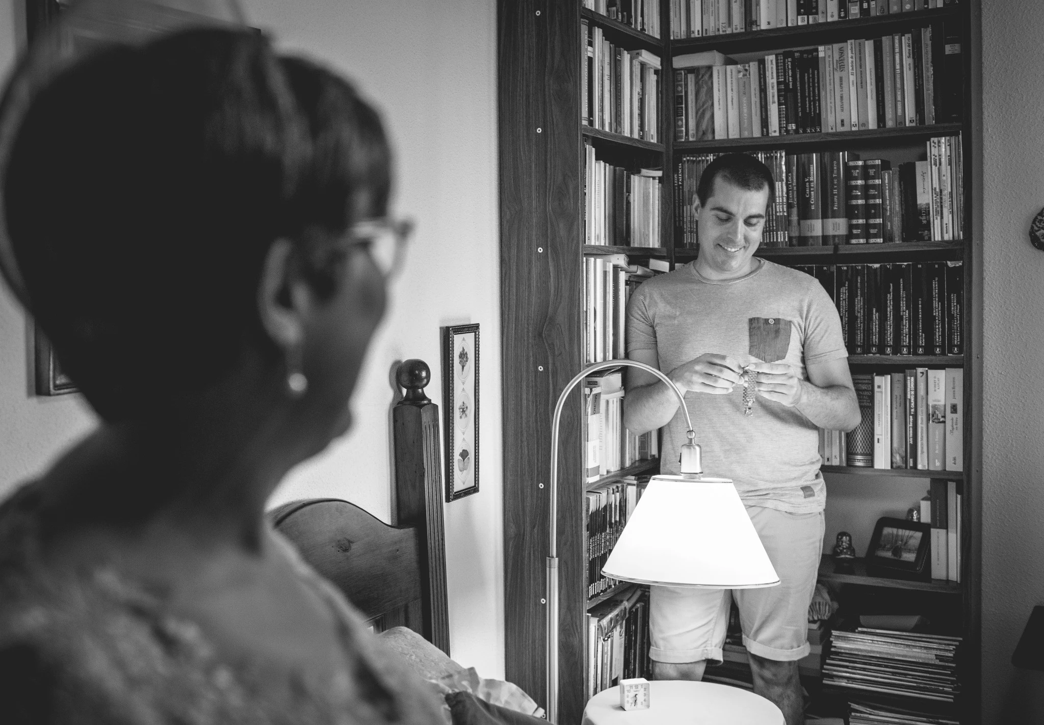 Novio observando un pequeño regalo mientras una familiar lo mira en primer plano.