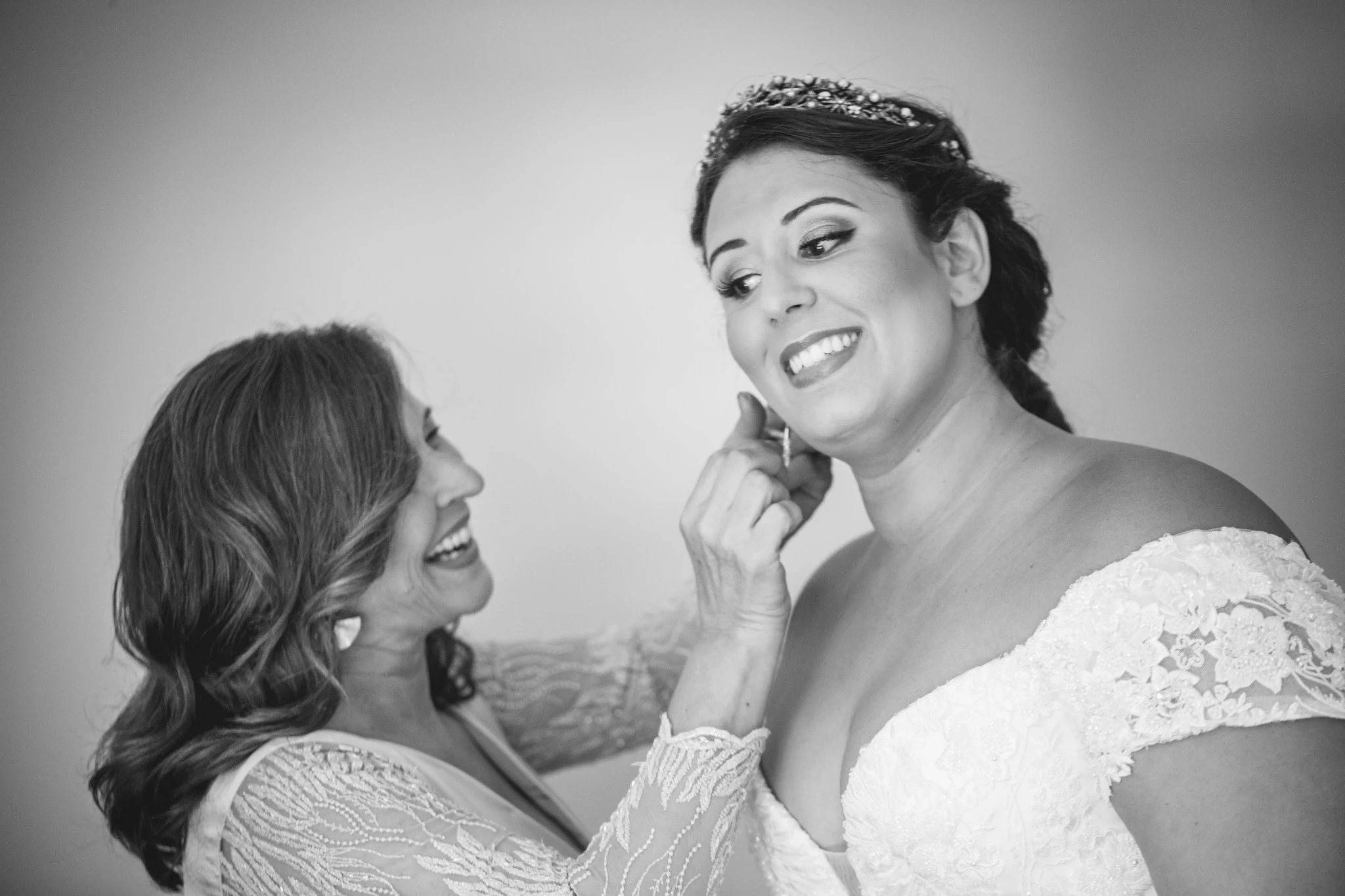 Una acompañante ayuda a la novia a colocarse un pendiente antes de la ceremonia.