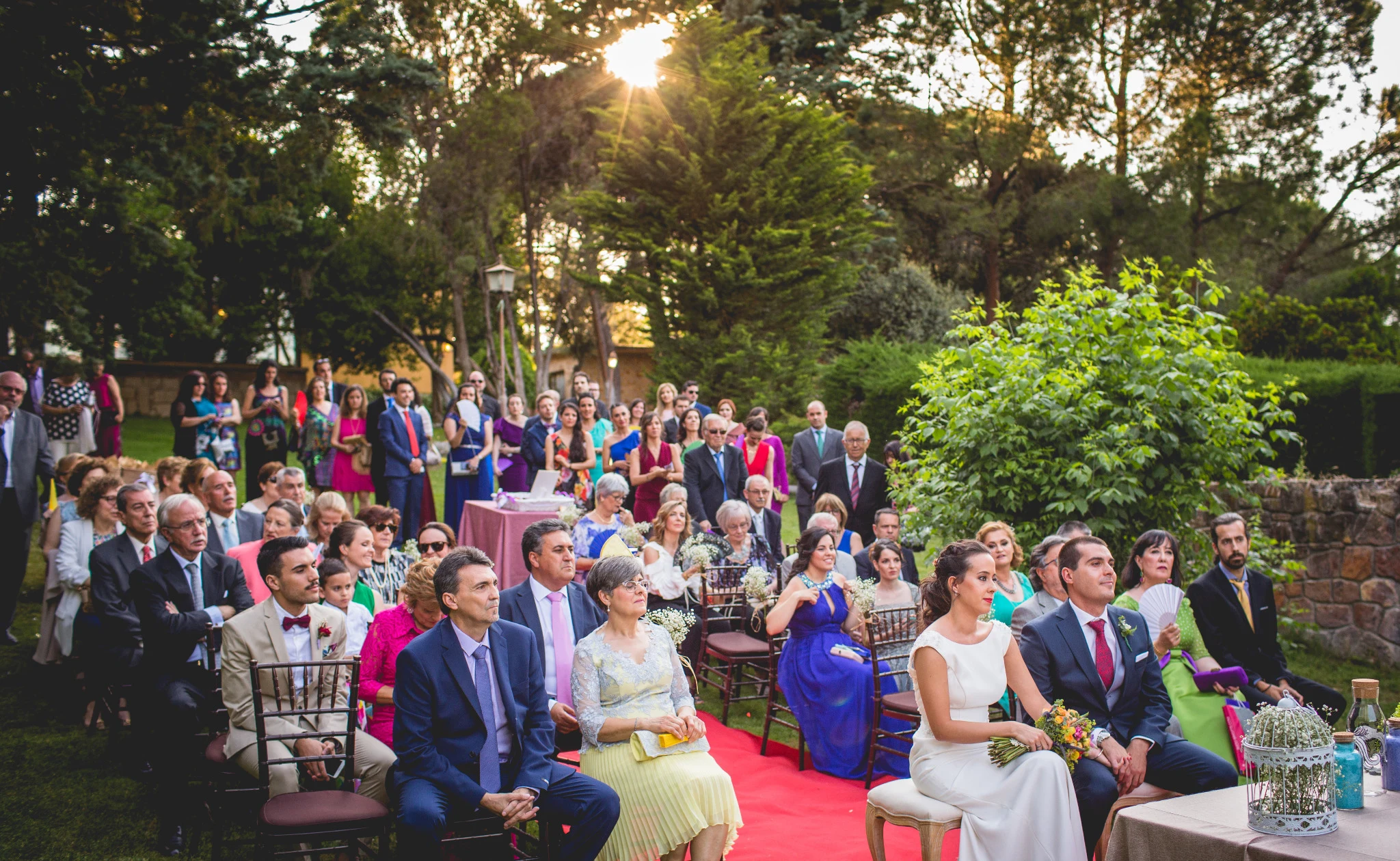 Vista general de una ceremonia civil con los novios y los invitados rodeados de árboles.