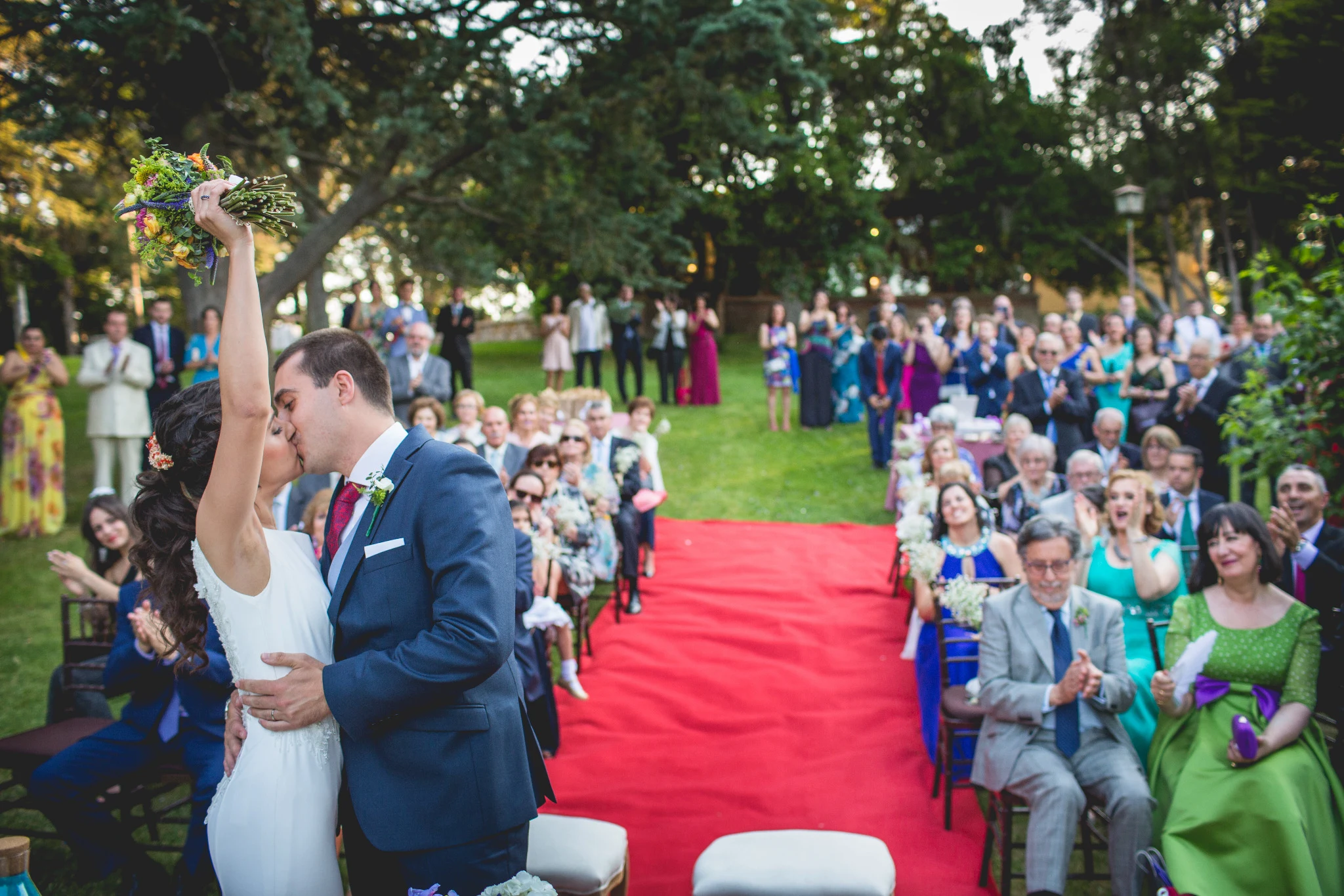 Novios besándose frente a los invitados al finalizar la ceremonia en el jardín.