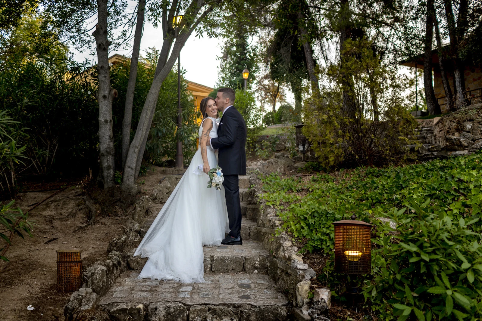 Novios se besan en el centro mientras los invitados se tapan los ojos de forma divertida.