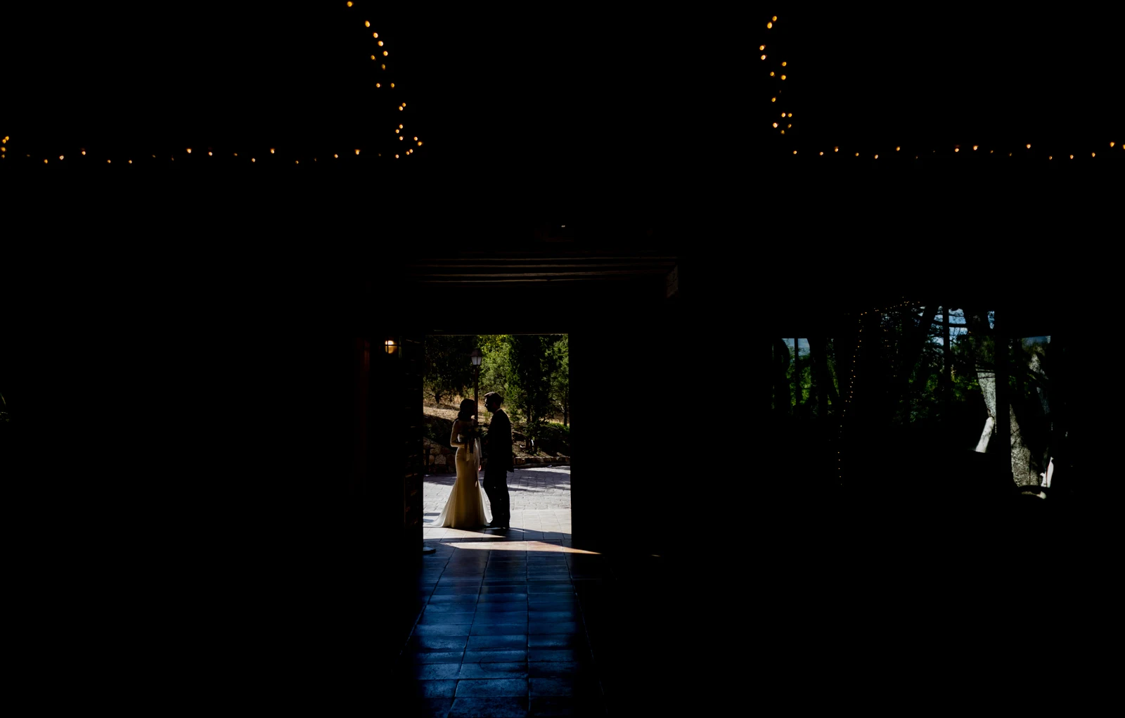 Novios en silueta besándose en la entrada iluminada de un edificio de la finca.