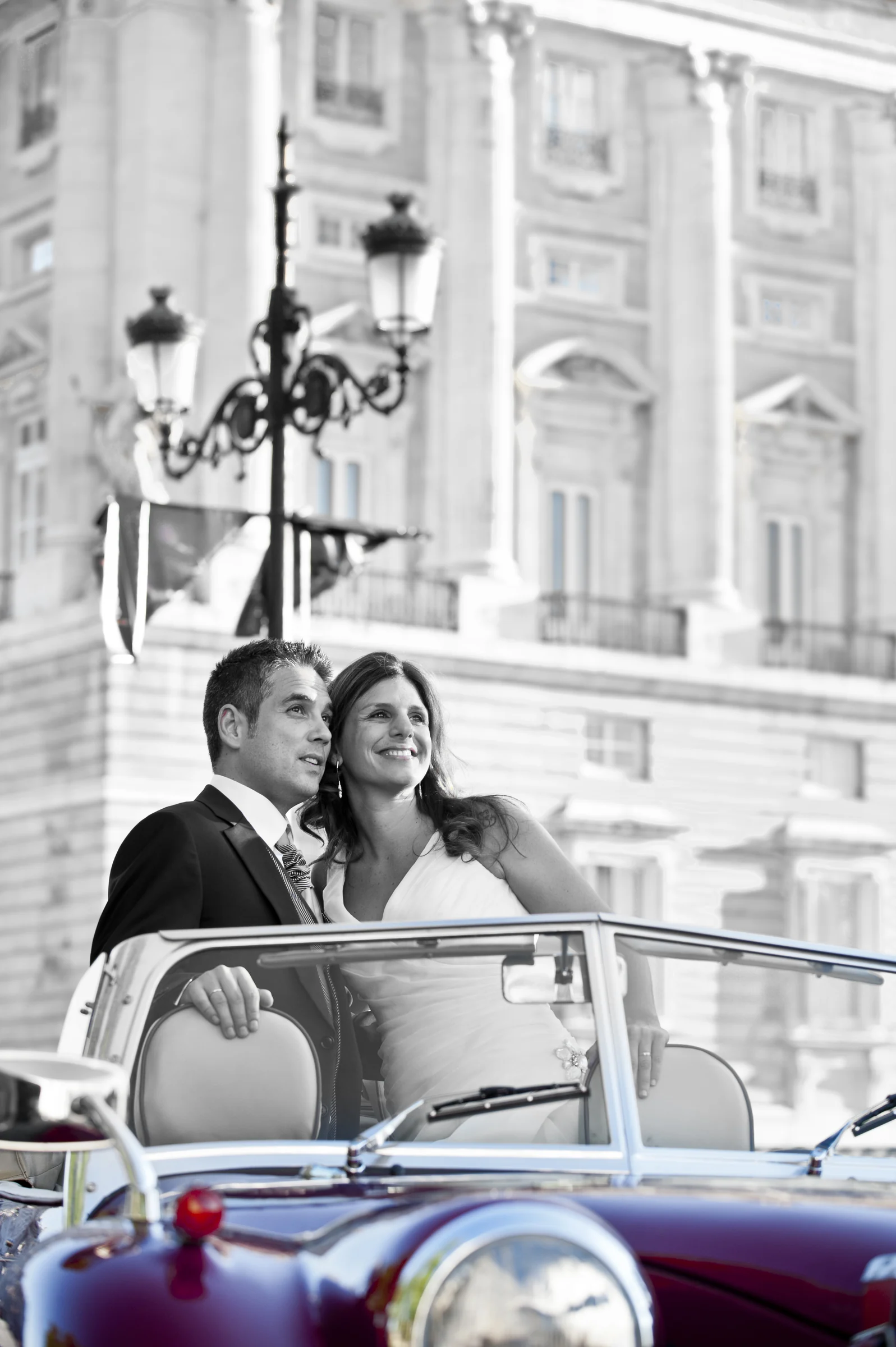 Retrato vertical en blanco y negro de una pareja de novios en el Hurtan con el Palacio Real de Madrid al fondo.