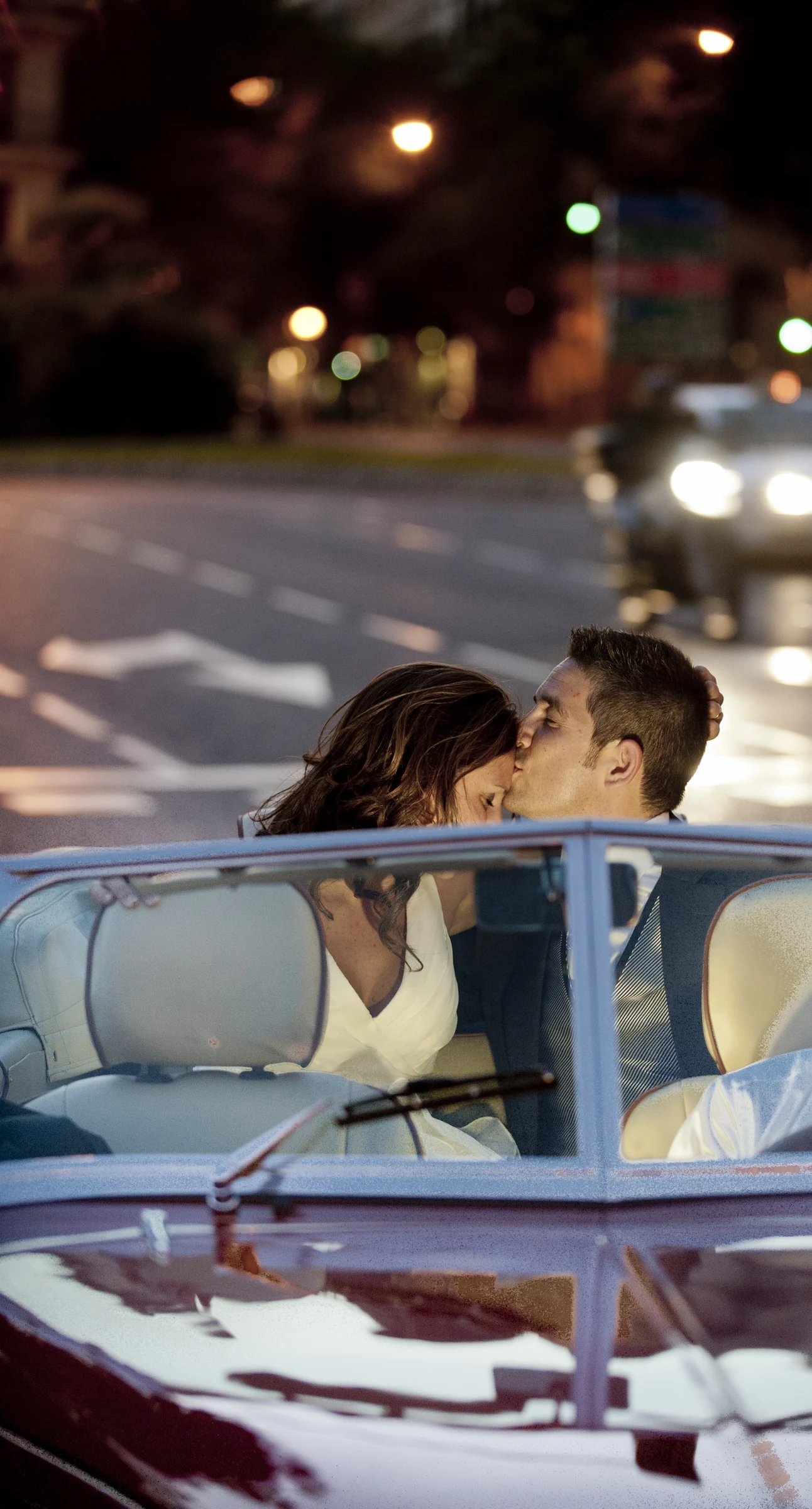 El novio besa a la novia dentro del Hurtan descapotable durante un trayecto nocturno por Madrid.