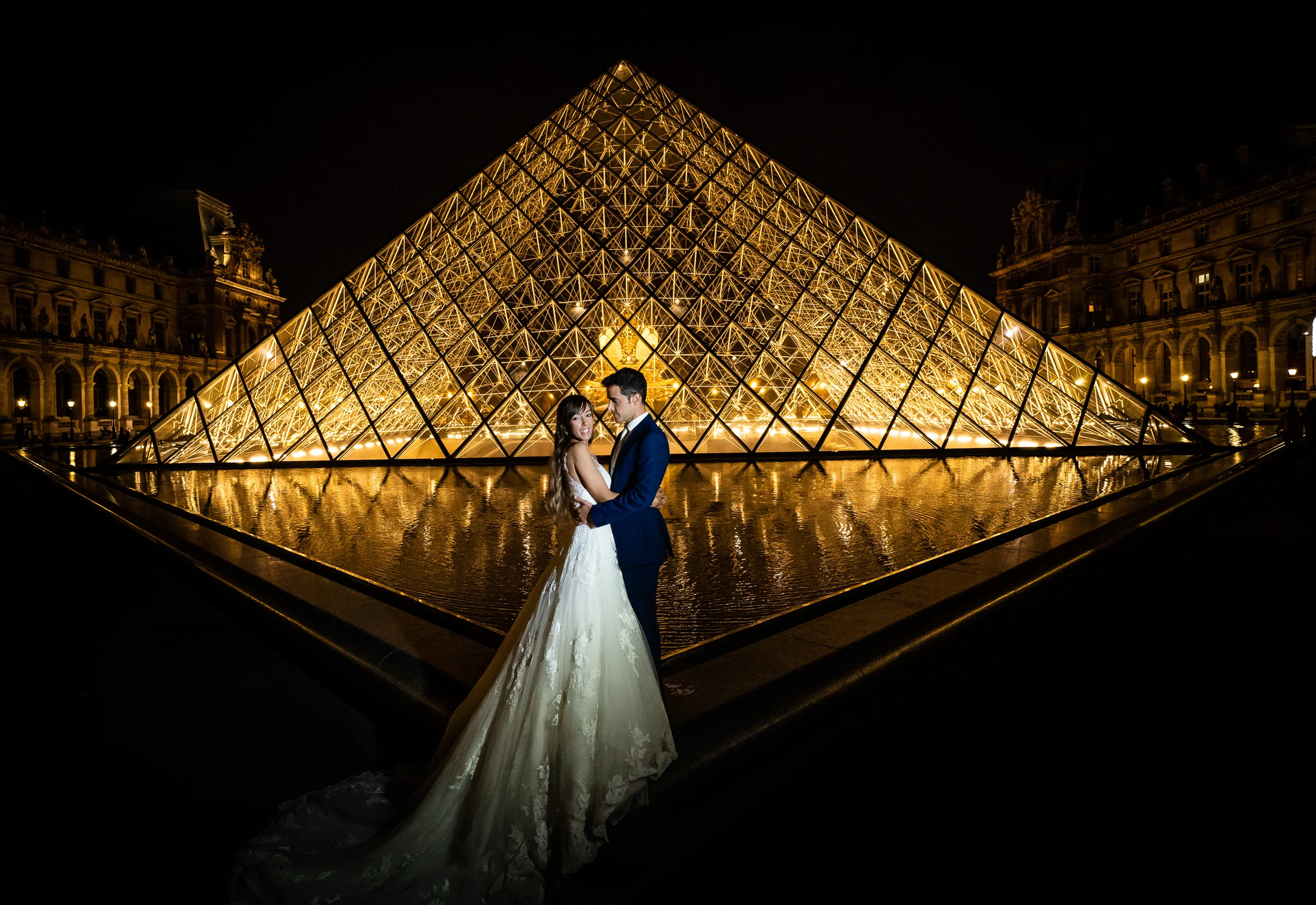 José Luis y Lara frente a la Pirámide del Louvre iluminada durante su postboda nocturna en París.