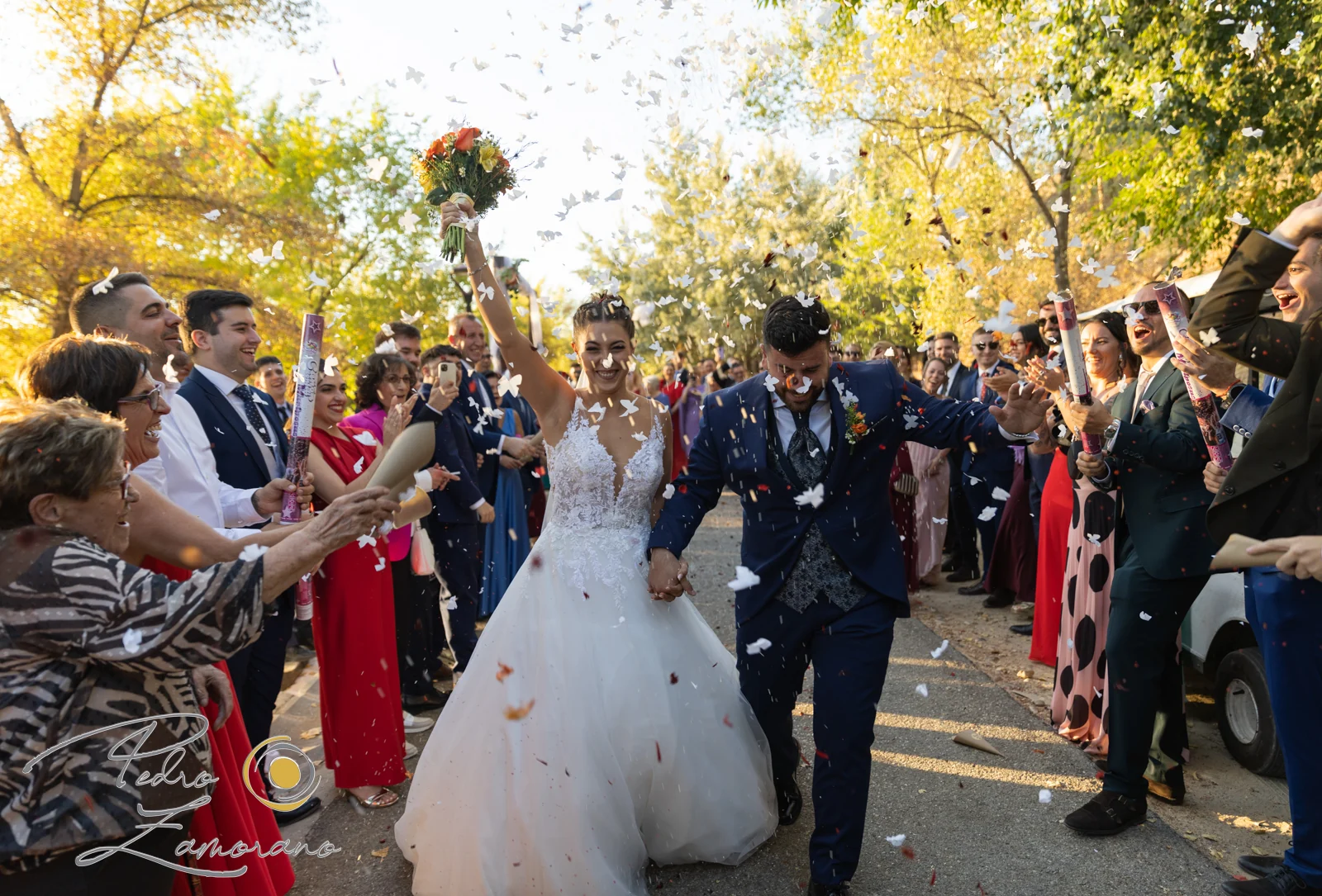 Salida de los novios entre invitados y pétalos en una boda en Complejo La Cigüeña