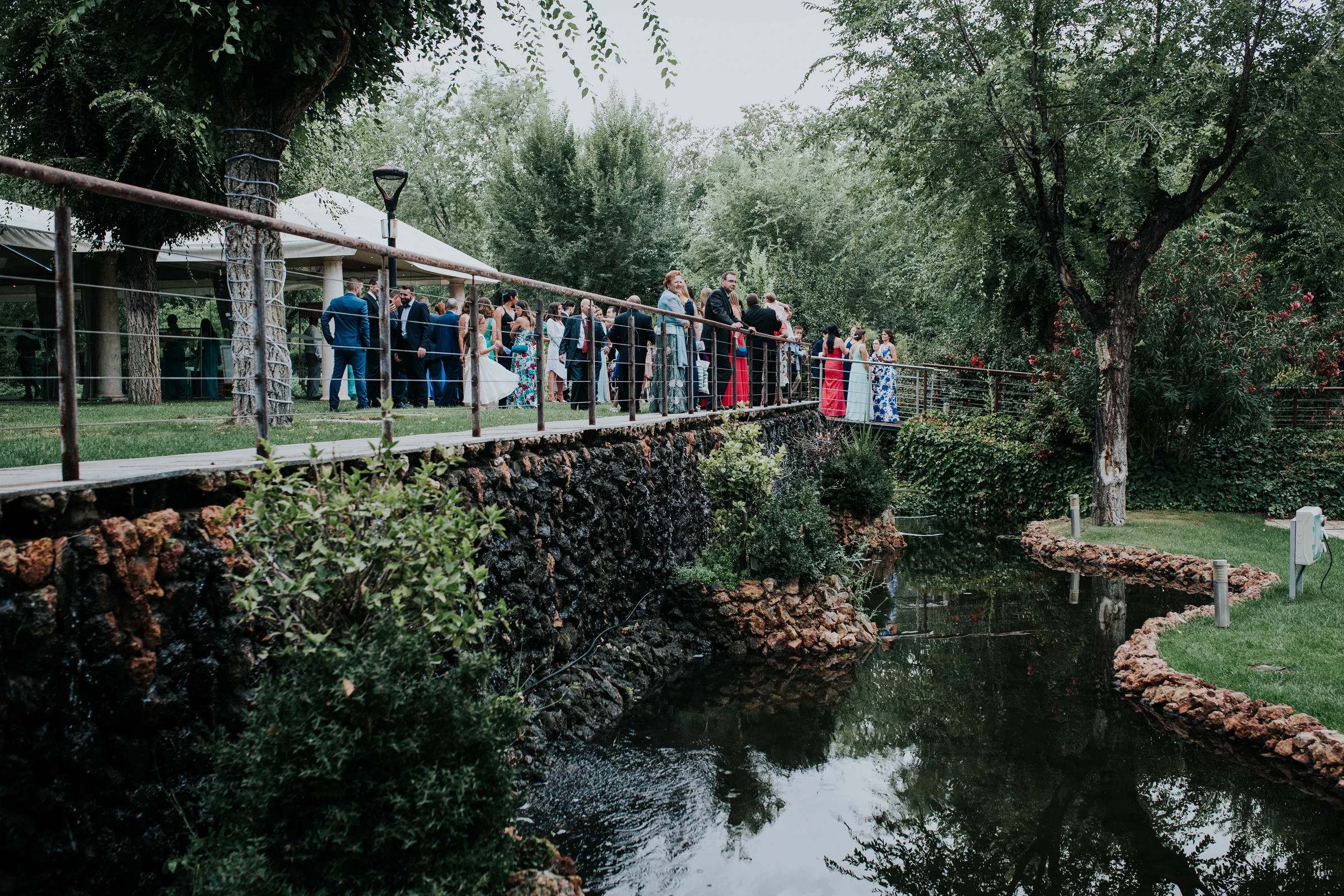 Pasarela sobre el lago con invitados en una boda en Complejo La Cigüeña