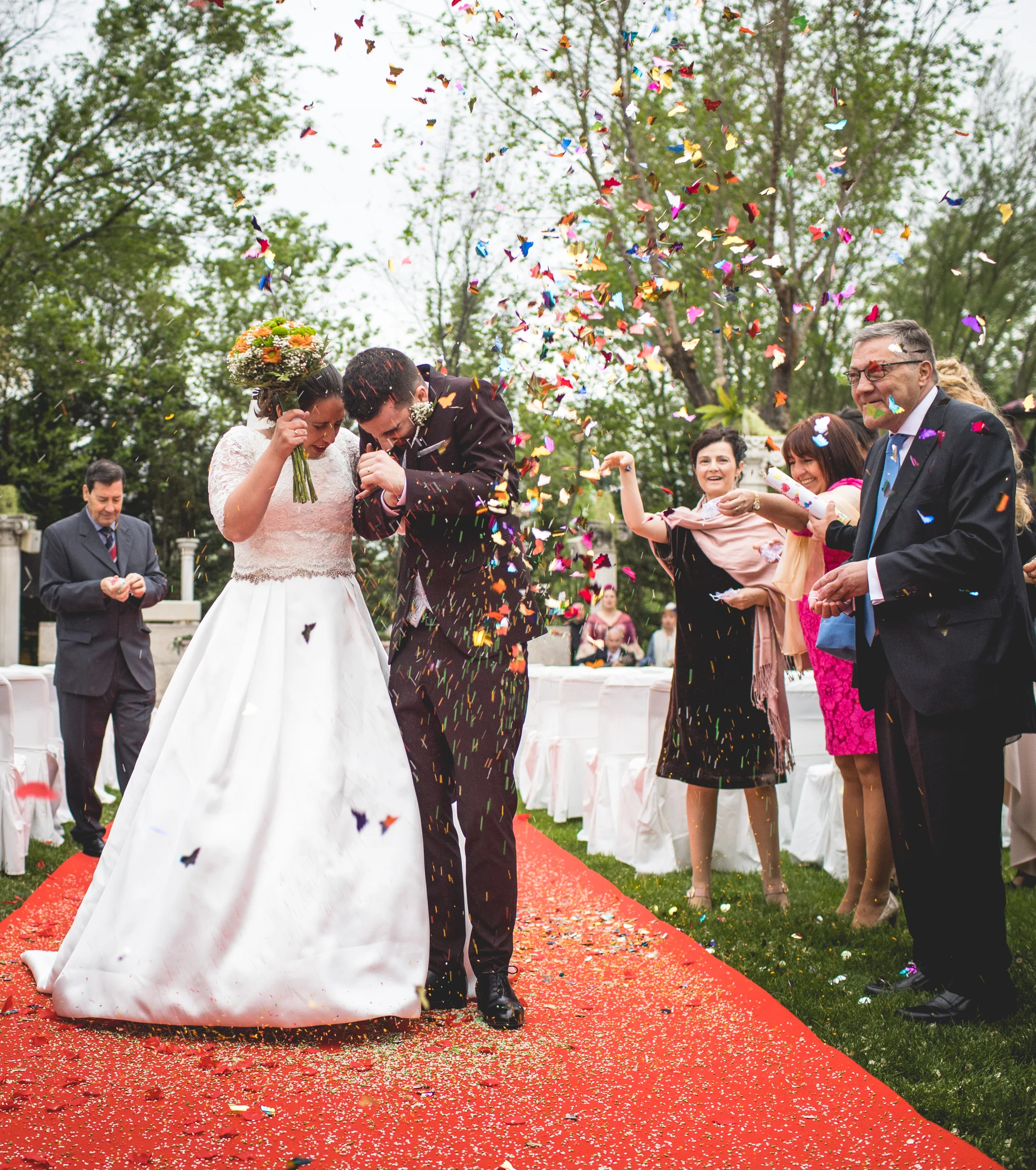 Novia celebrando entre pétalos durante la salida en una boda en Complejo La Cigüeña