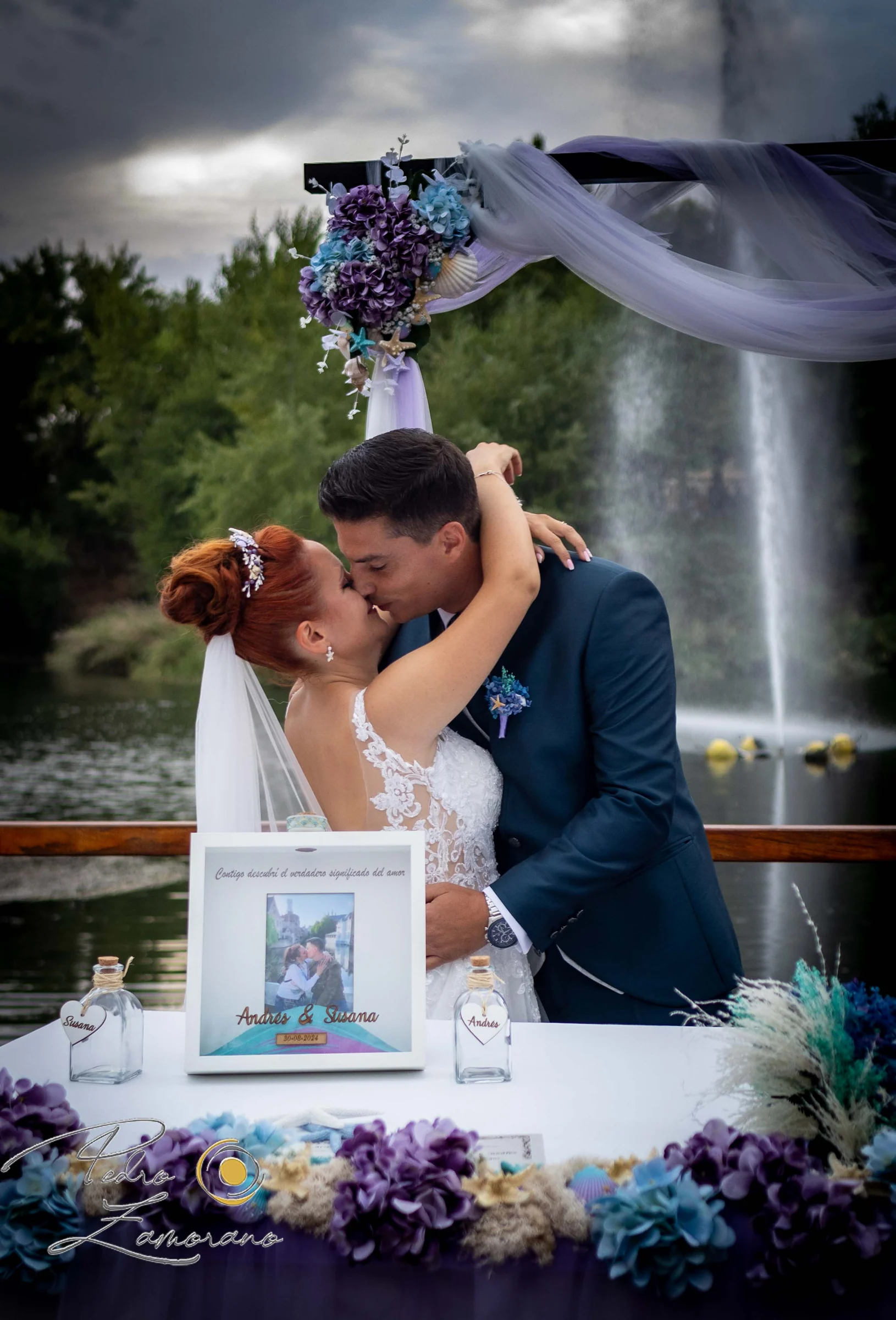 Novios besándose junto a decoración floral en una boda en Complejo La Cigüeña