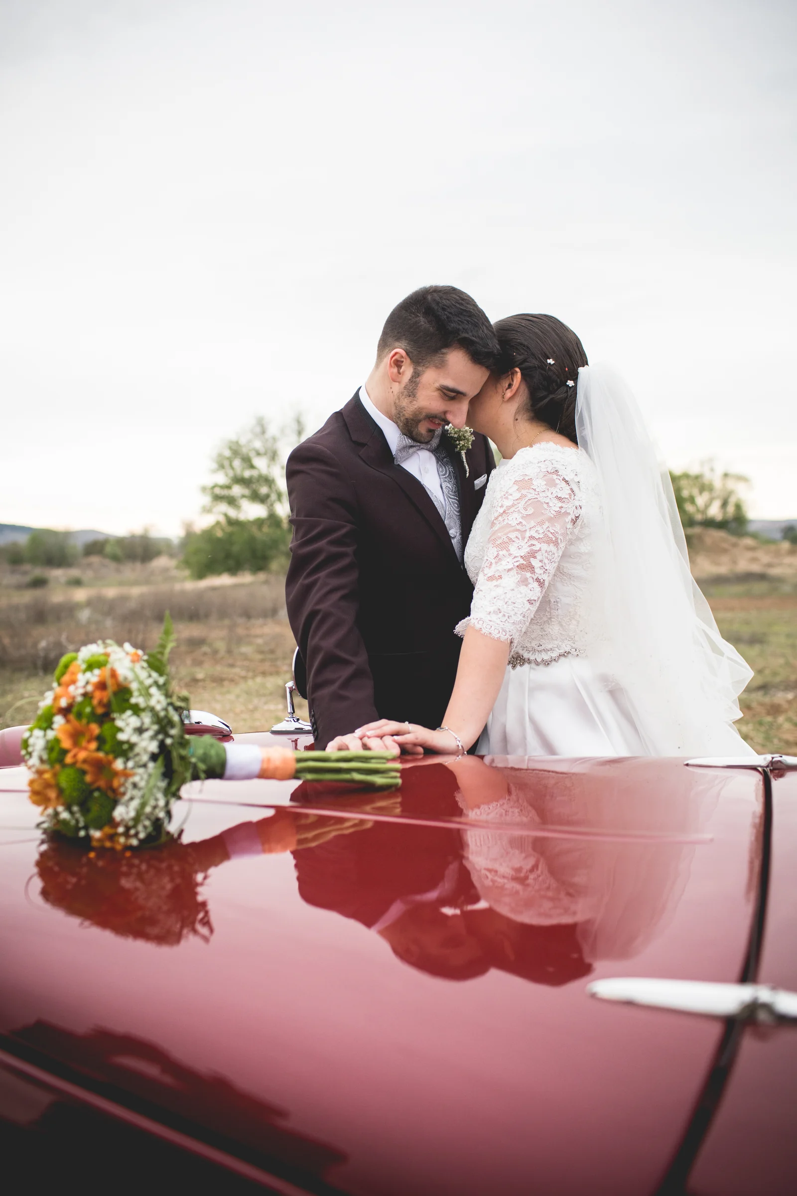 Novios reflejados en el coche clásico en una boda en Complejo La Cigüeña