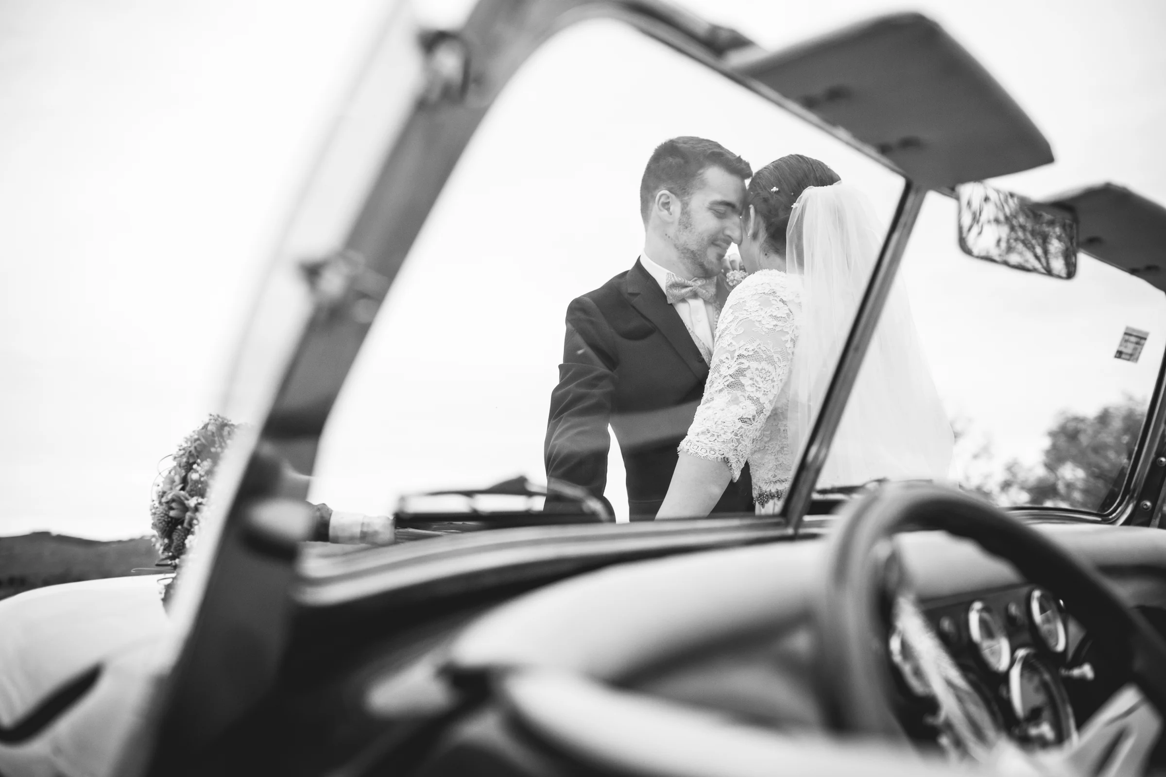 Novios en coche clásico en blanco y negro en una boda en Complejo La Cigüeña
