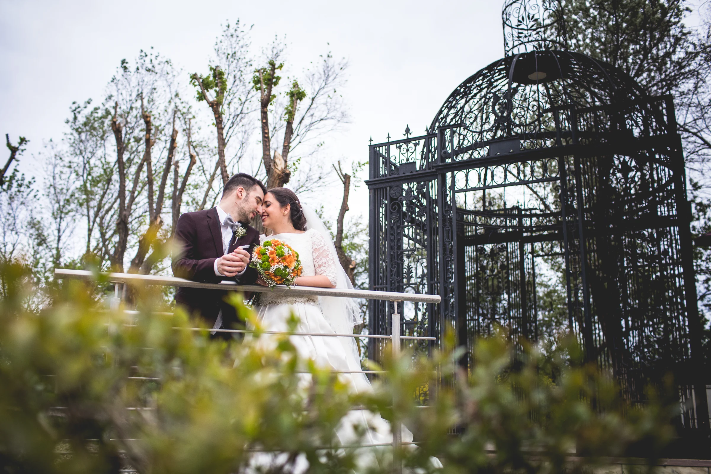 Novios junto a estructura metálica del jardín en una boda en Complejo La Cigüeña