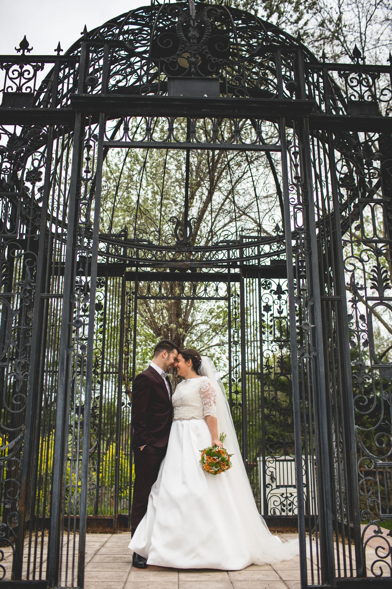 Novia en retrato vertical en un jardín en una boda en Complejo La Cigüeña