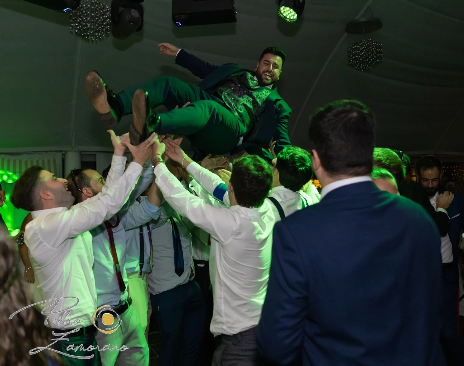 Invitados levantando a una persona durante la fiesta en una boda en Complejo La Cigüeña
